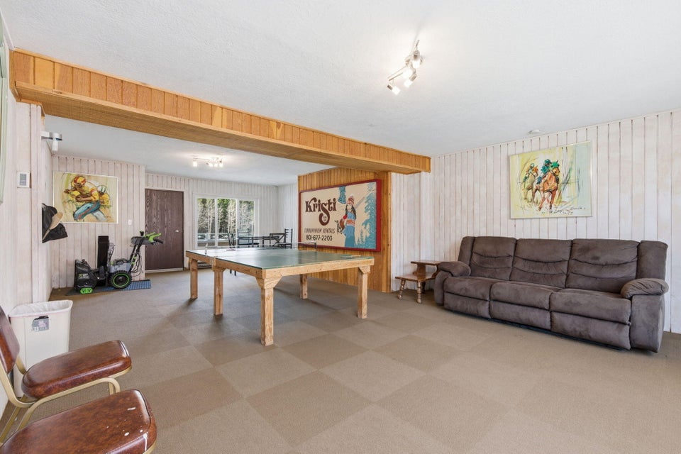 Spacious recreation room featuring a large open area with durable flooring, white paneled walls, and wood-finish exposed beams