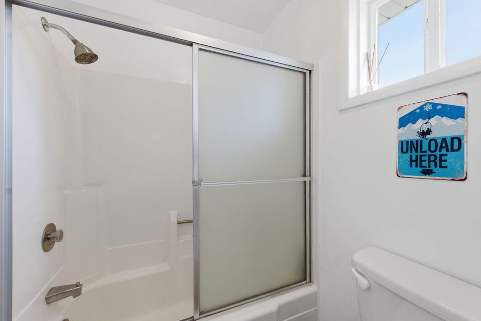 White shower-tub combination featuring brushed nickel fixtures and a sliding frosted glass enclosure