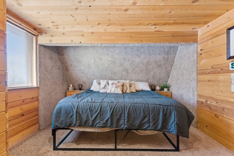 Wood-paneled walls and ceiling surround a built-in bed alcove featuring textured wall finishes