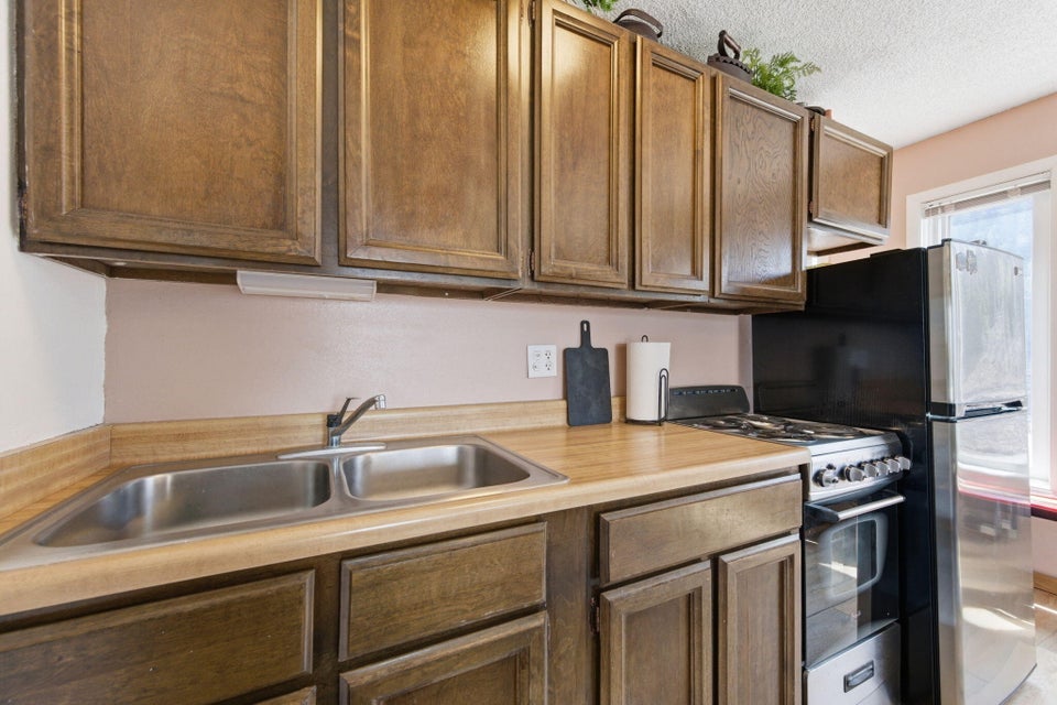 Kitchen featuring wood-finish cabinetry, a double basin stainless steel sink, a gas range with an oven, and a refrigerator with a stainless steel door panel