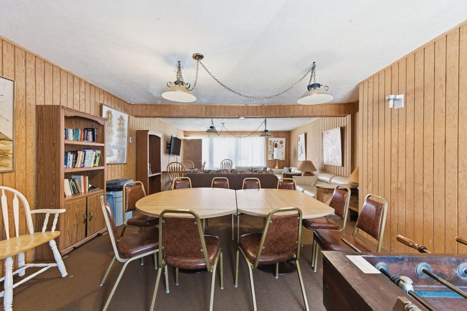 Spacious common area featuring wood-finish paneling, drop ceiling, and multiple pendant light fixtures