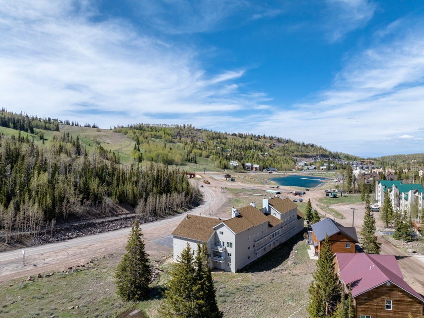 Mountainous landscape featuring a prominent body of water, extensive tree coverage, and multiple residential structures