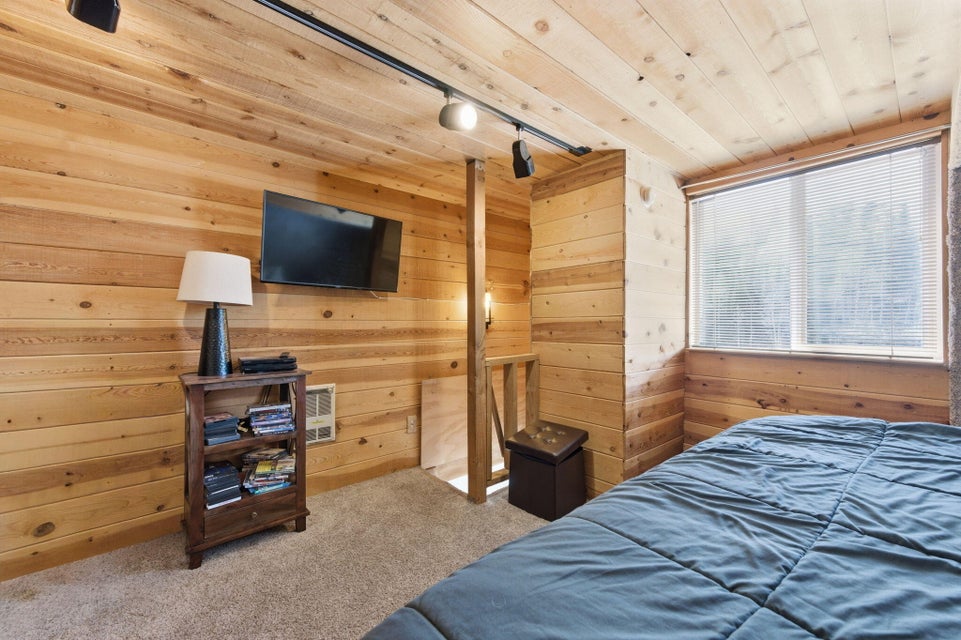 Wood-paneled room featuring track lighting and a large window with blinds