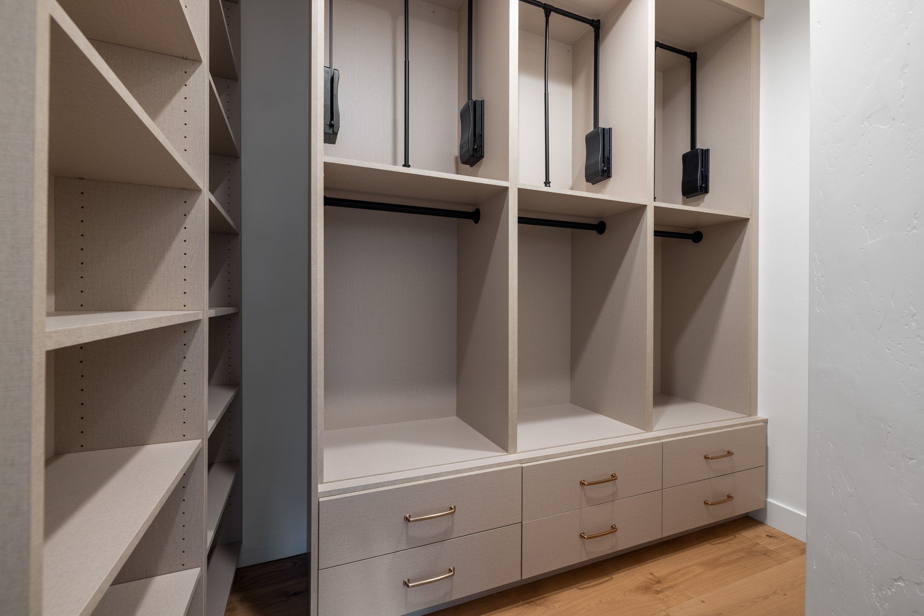 Custom closet system featuring built-in shelving, integrated drawers with hardware, multiple hanging rods, and adjustable upper hanging mechanisms
