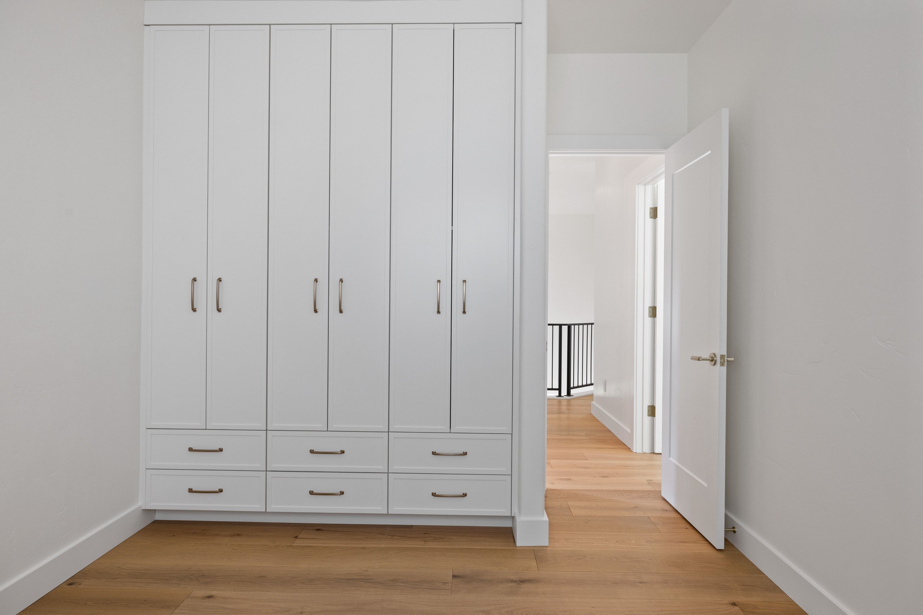 Integrated white cabinetry with brushed nickel hardware, wood-finish flooring, and white baseboards