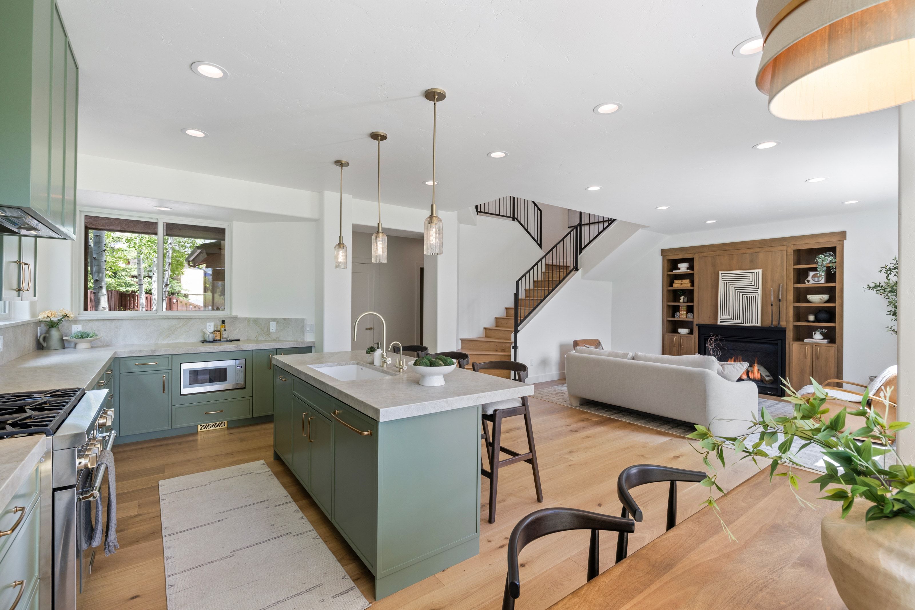 Contemporary kitchen featuring sage cabinetry, stainless steel appliances, and a central island with a built-in sink