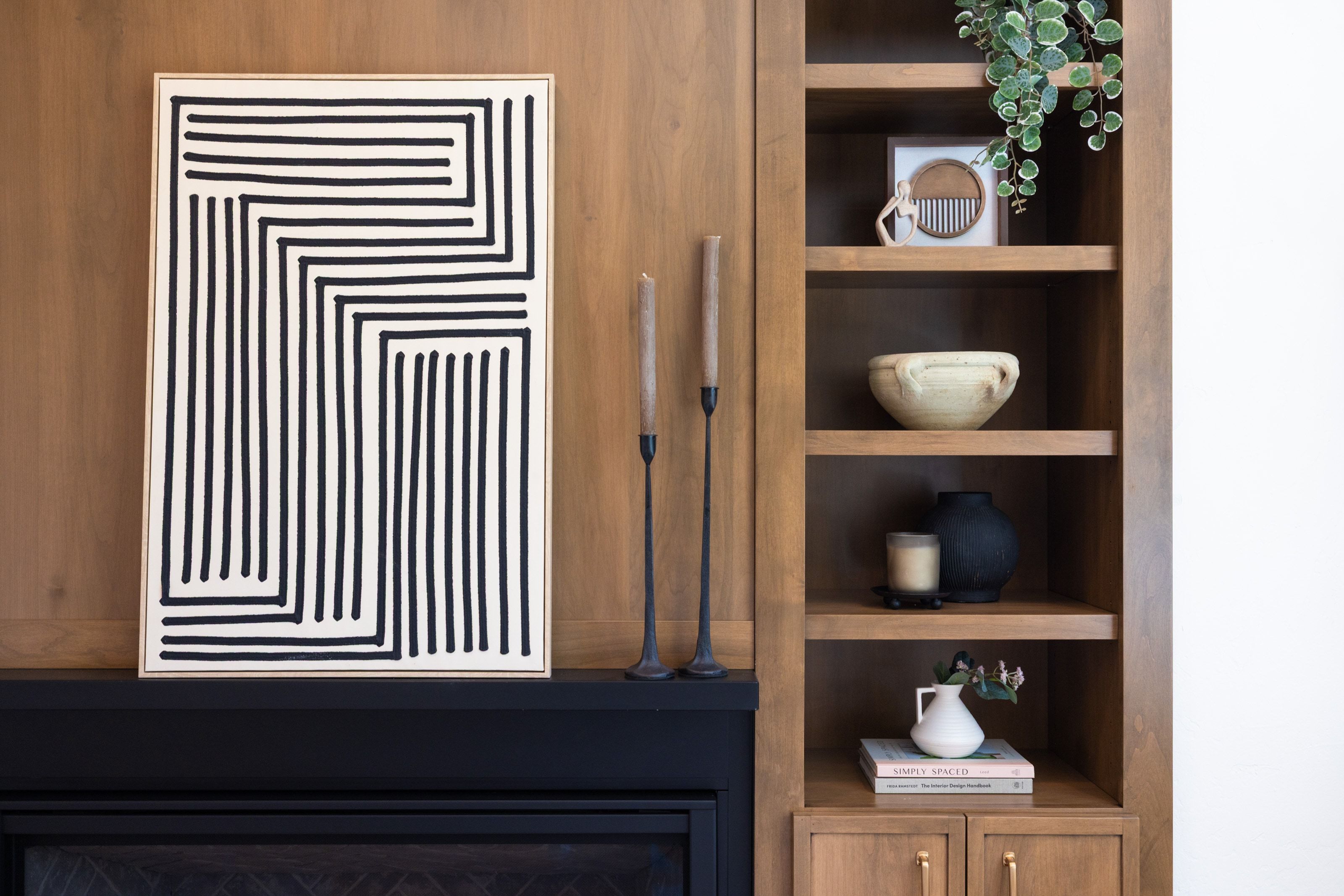 Built-in wood-finish shelving with integrated base cabinetry and brass hardware, featuring a coordinating wood-finish wall panel