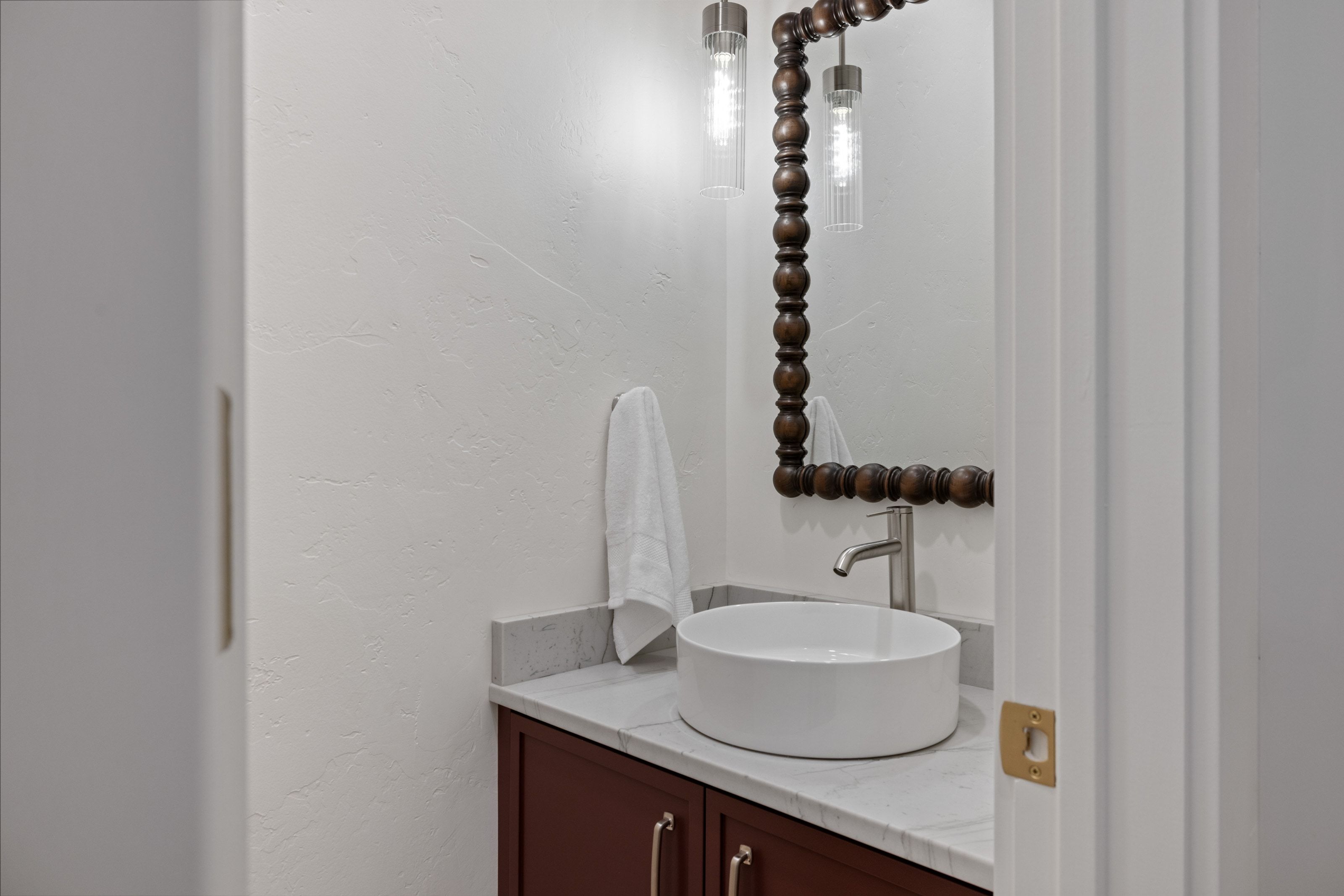 Powder room featuring a vessel sink, stone countertop, custom wood vanity, ornate wood-framed mirror, and modern pendant lighting
