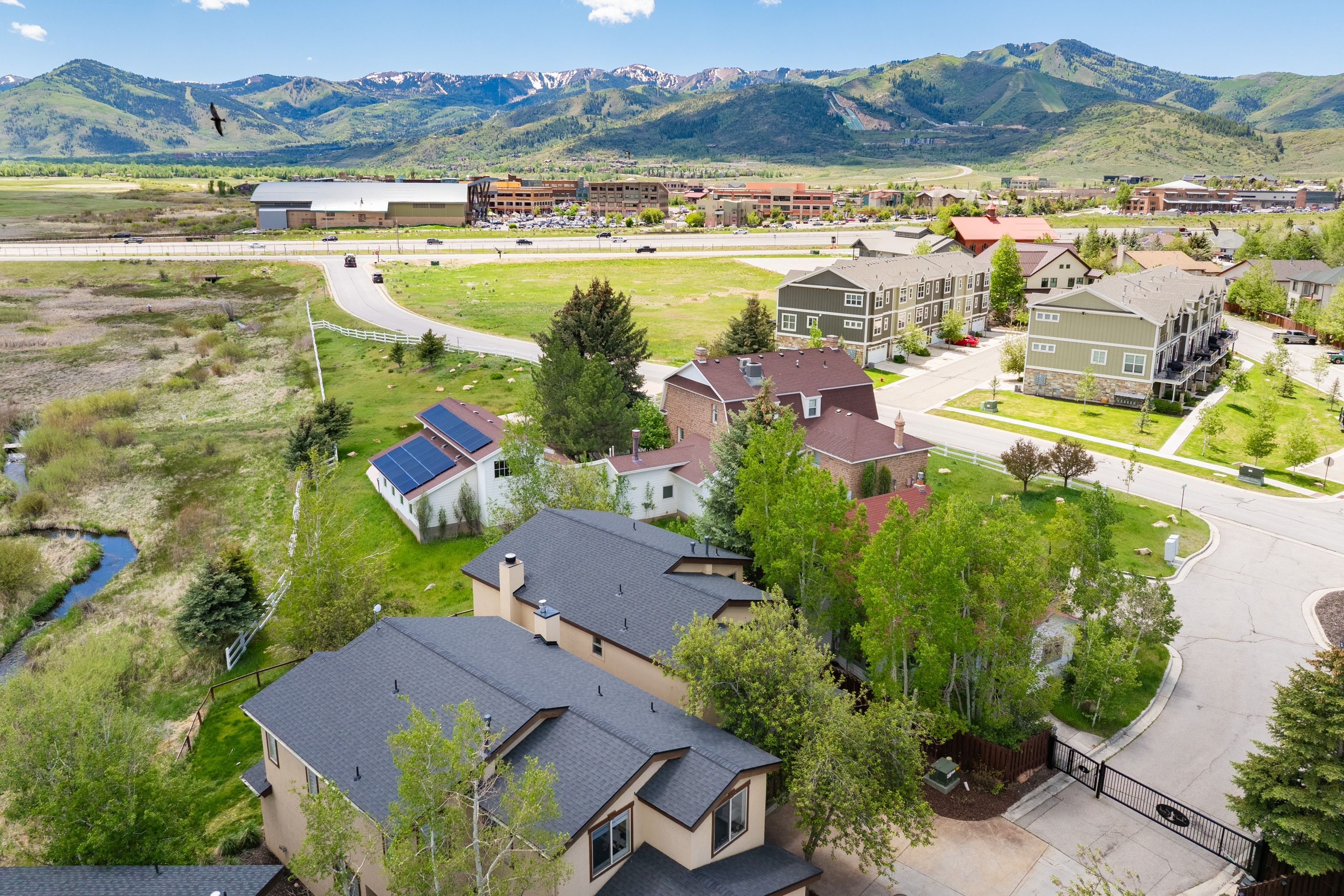 Aerial perspective showcasing a residential area with varied housing styles, mature trees, and mountainous terrain in the background