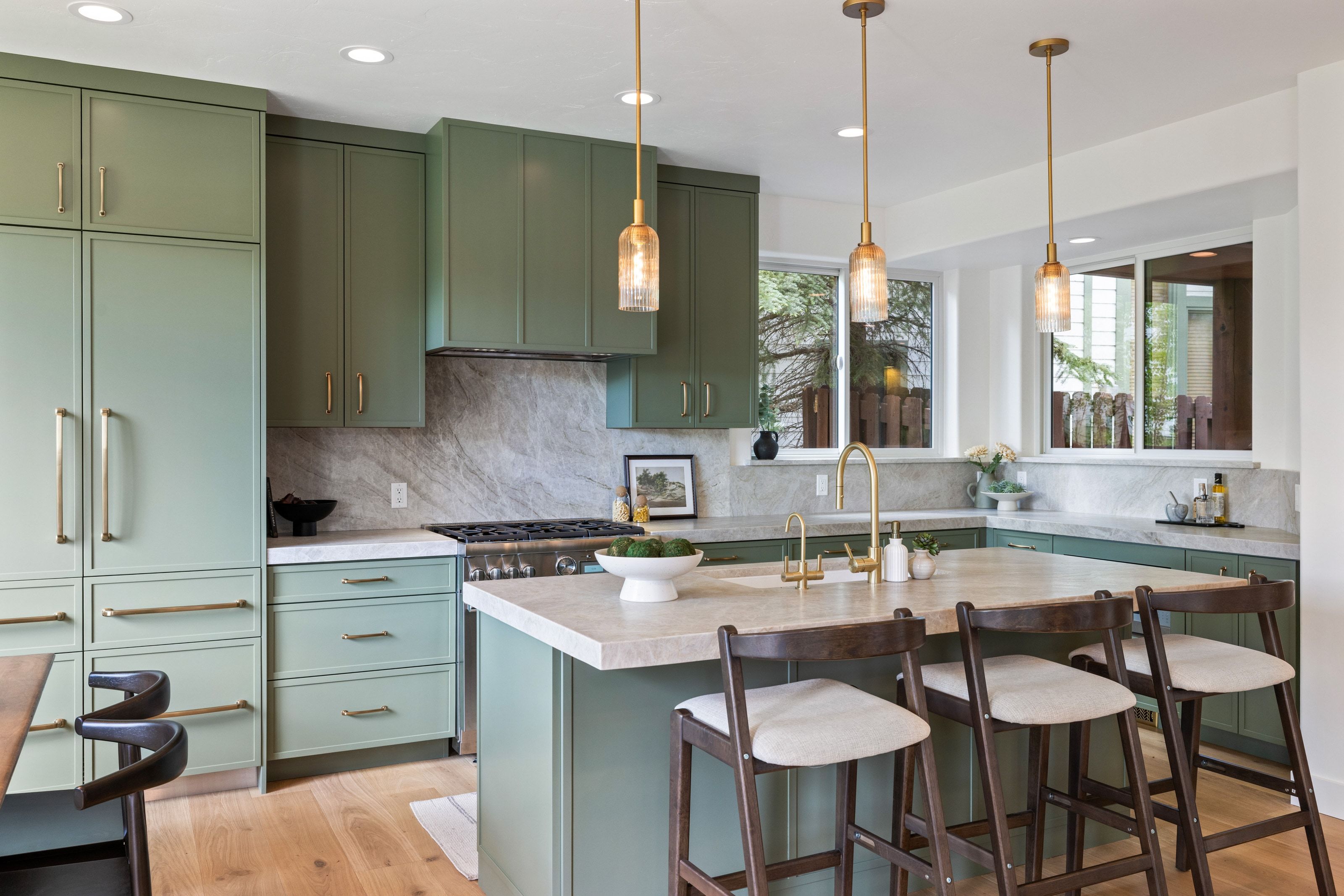 Kitchen featuring sage green cabinetry, a large center island with seating, integrated refrigerator, stone countertops, and a gas range with a matching stone backsplash