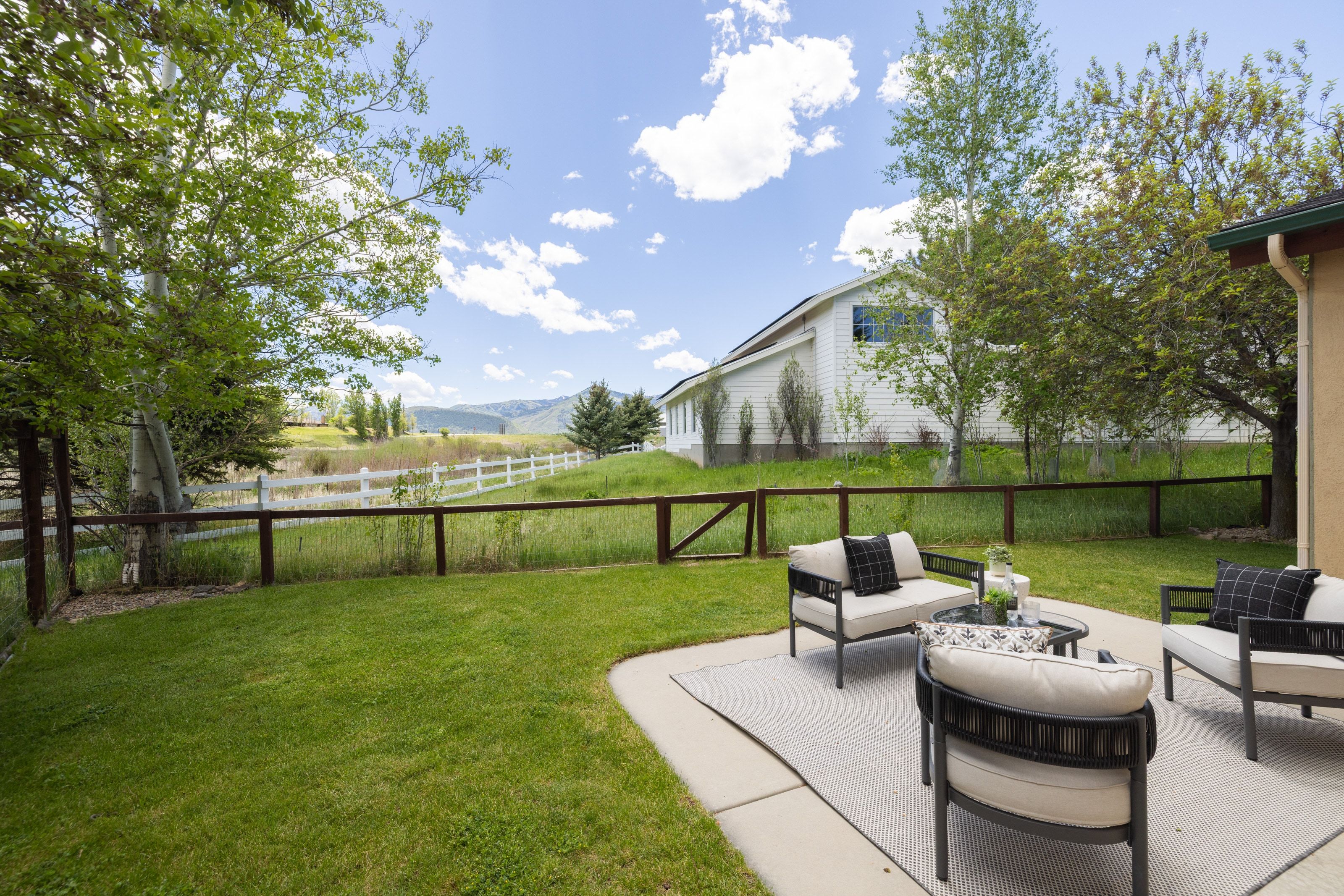 Outdoor patio featuring a concrete surface and a white picket fence bordering a grassy area