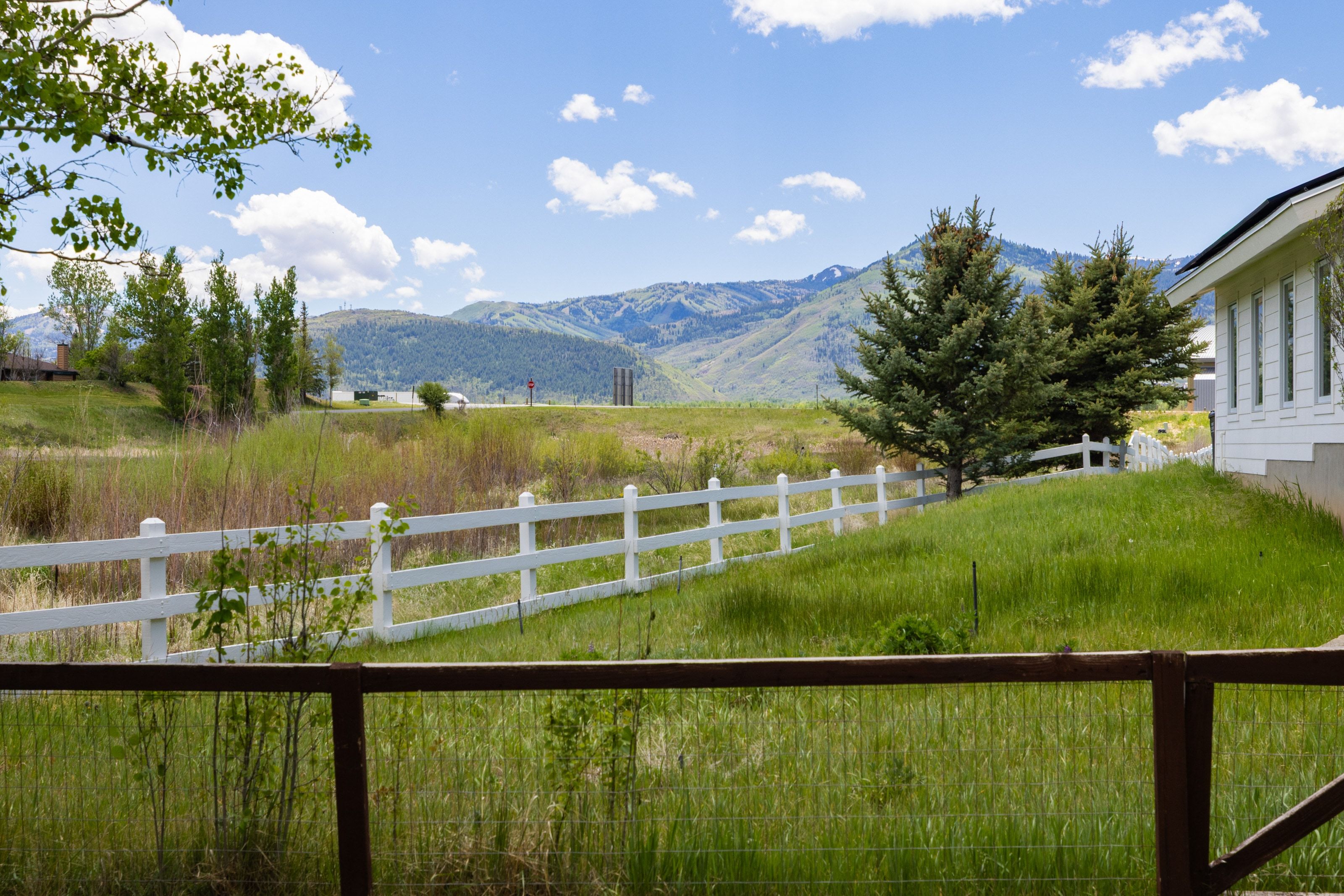Expansive natural landscape with a white picket fence bordering a grassy area