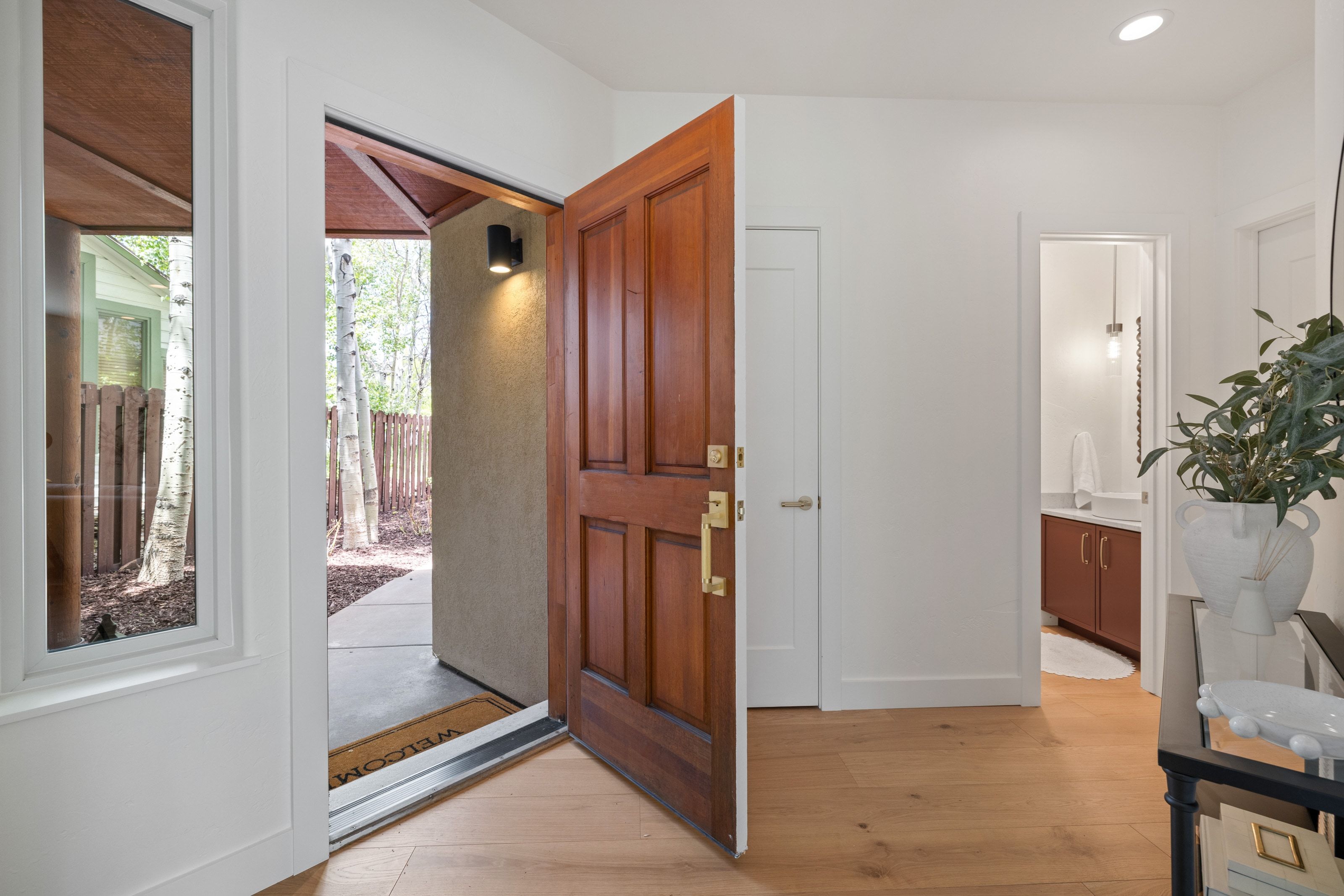 Panel-paneled entry door with brass hardware opens to wood-finish flooring