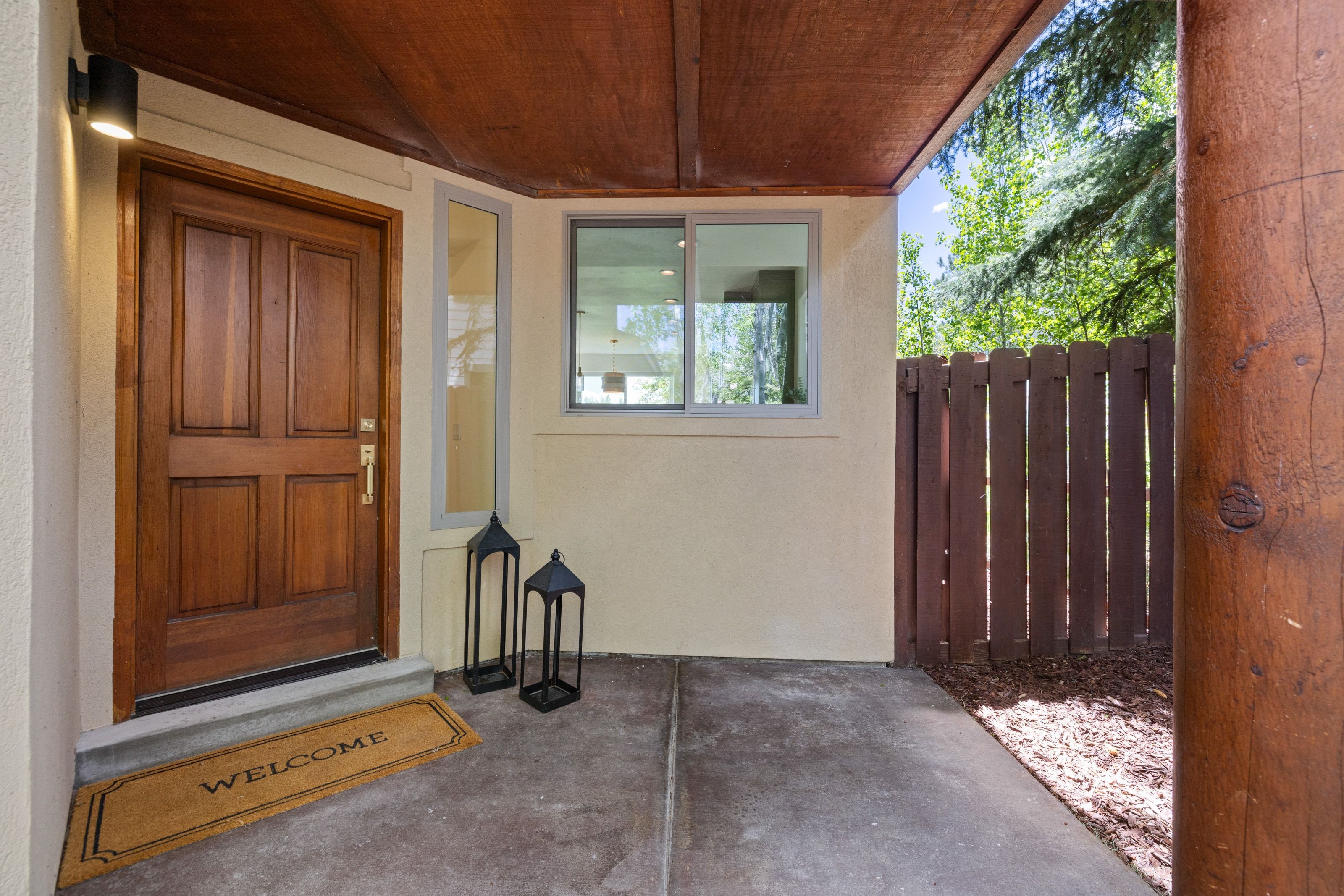Covered entryway featuring a paneled wood door with a sidelight, stucco exterior, and a wood-paneled soffit