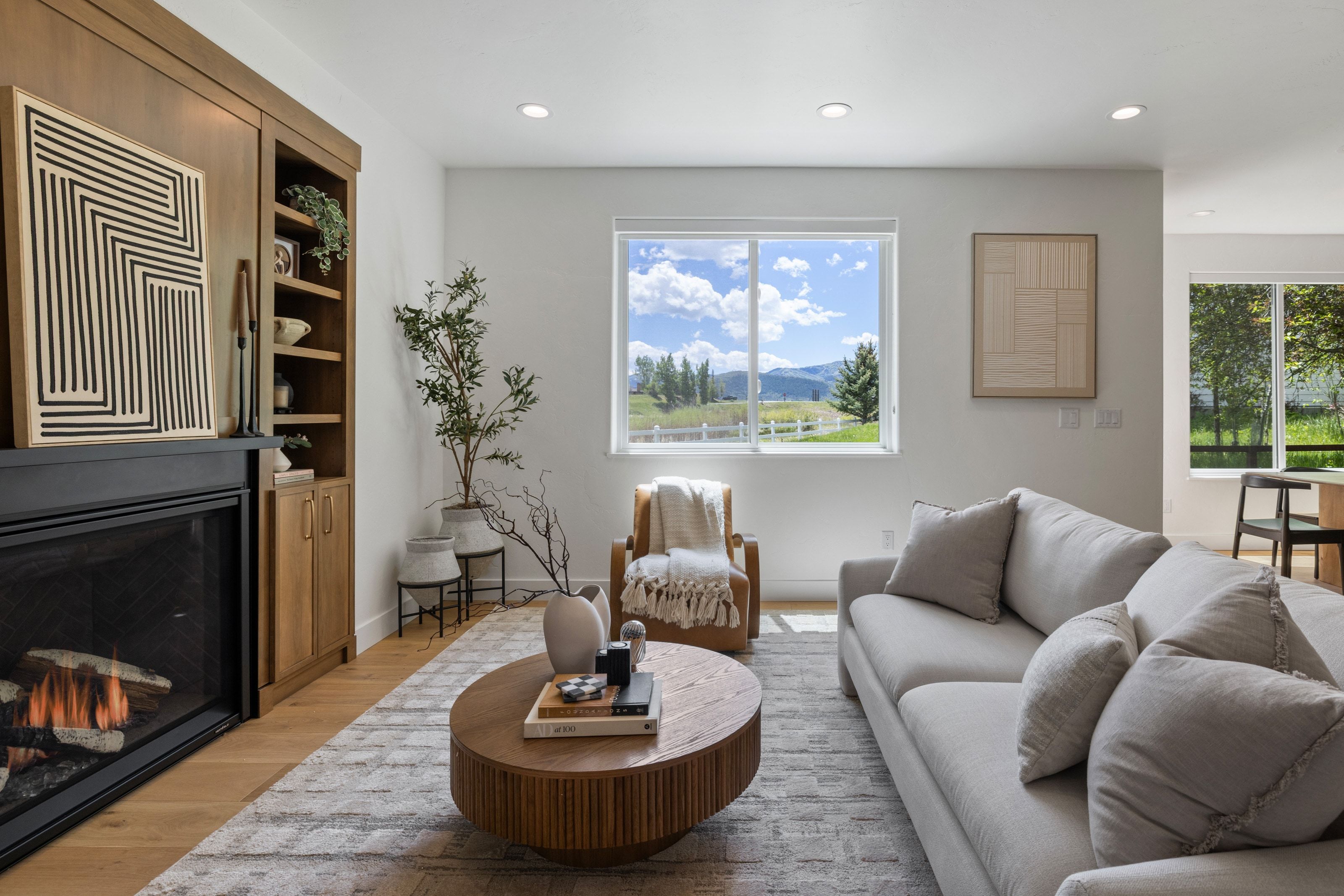Living area featuring a built-in fireplace with a black surround, integrated wood-finish shelving, recessed lighting, and wood-finish flooring