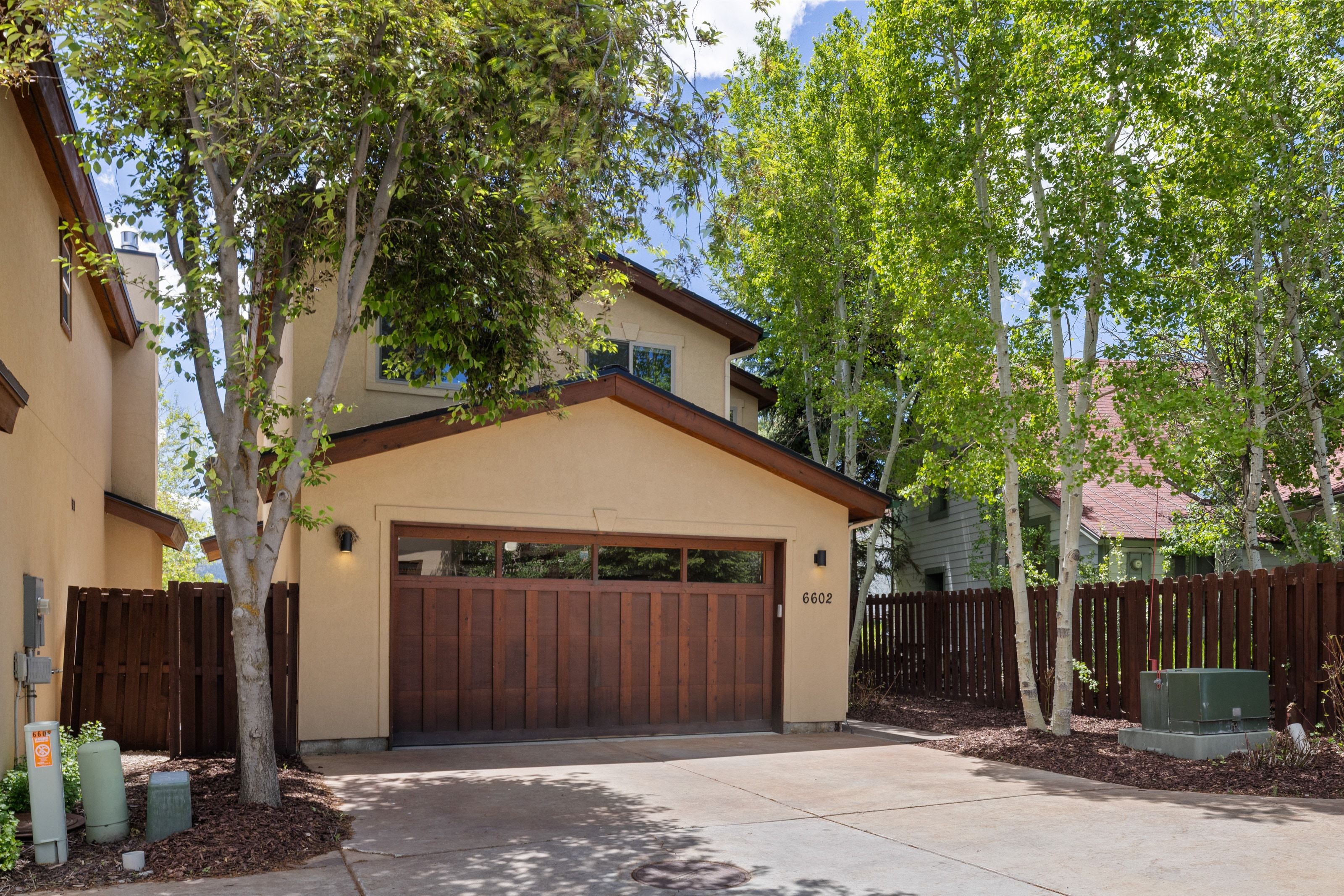 Exterior stucco residence featuring a dark wood-finish garage door with upper-level window panels