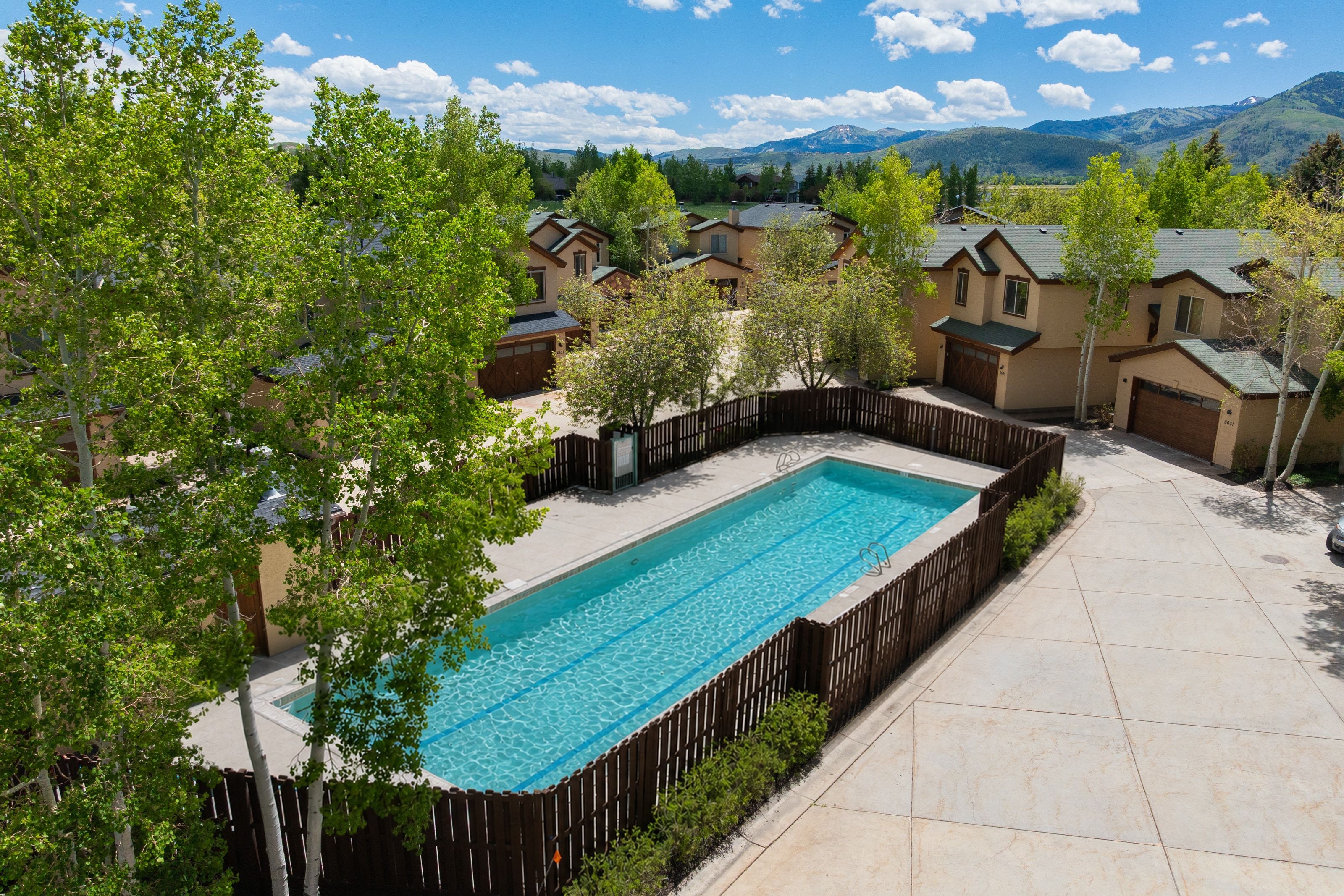 Outdoor swimming pool with surrounding privacy fence and concrete decking