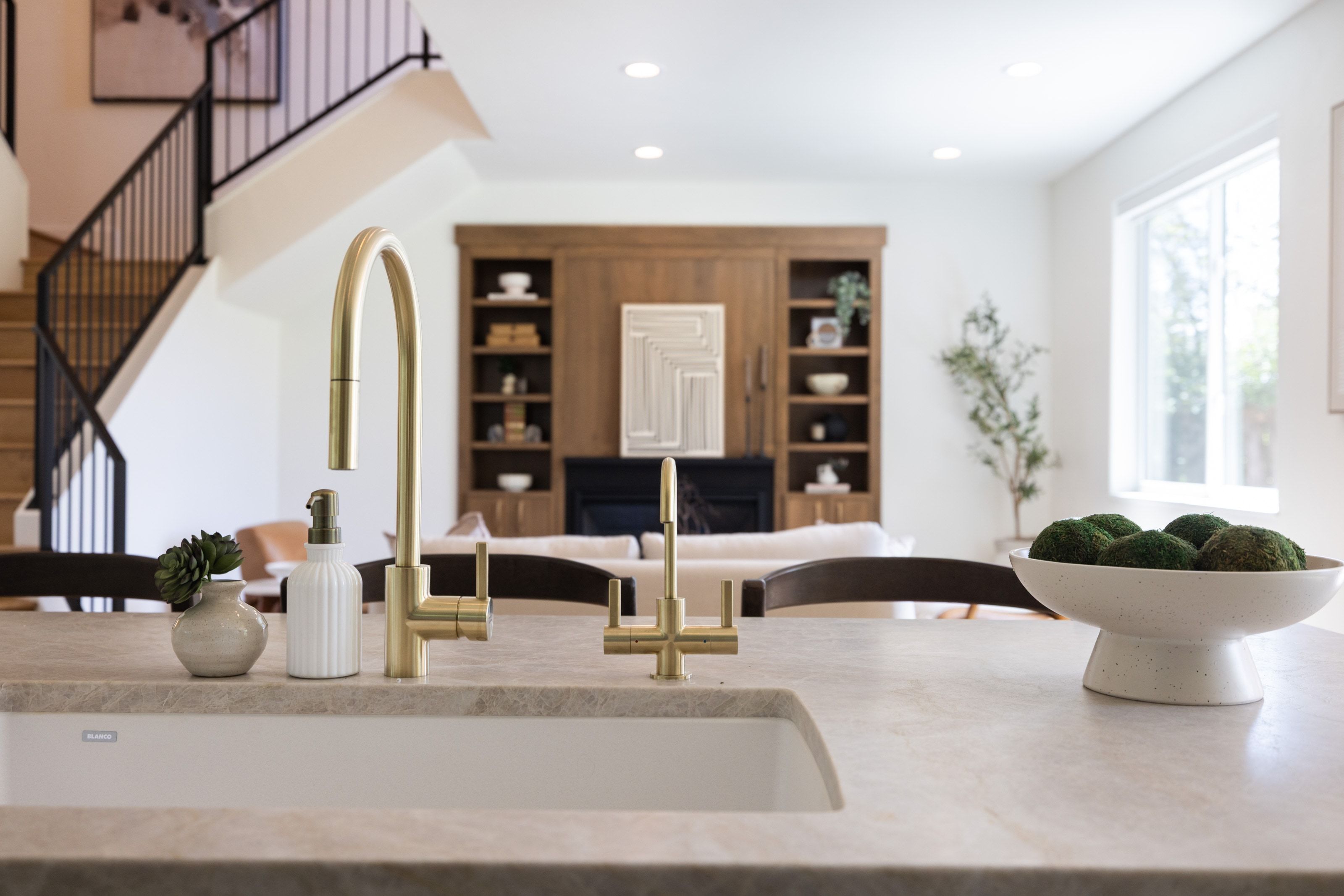 Kitchen island featuring an undermount sink, brass finish faucet, and stone-finish countertop