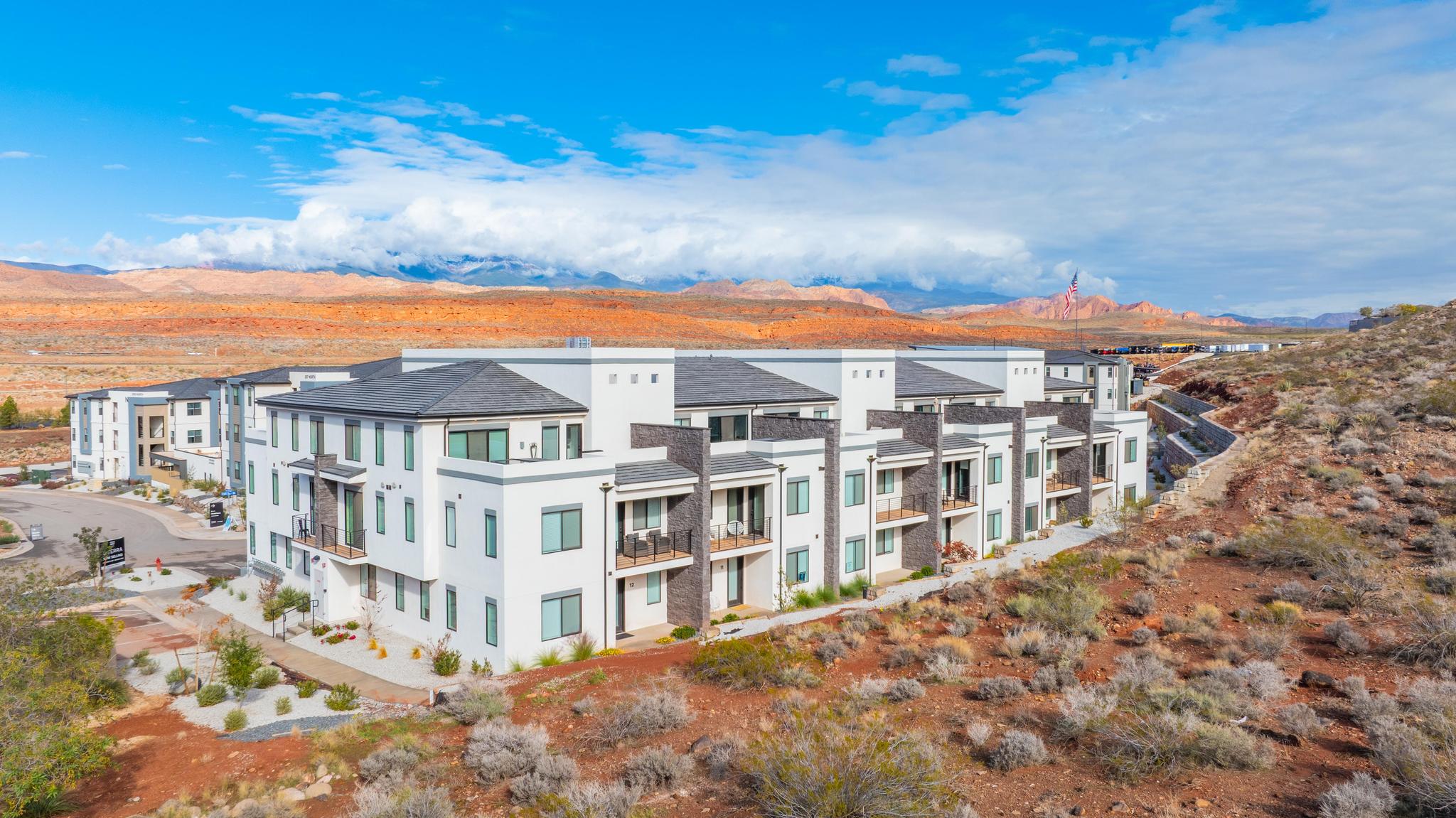 Modern multi-story residential building with white stucco and stone accents