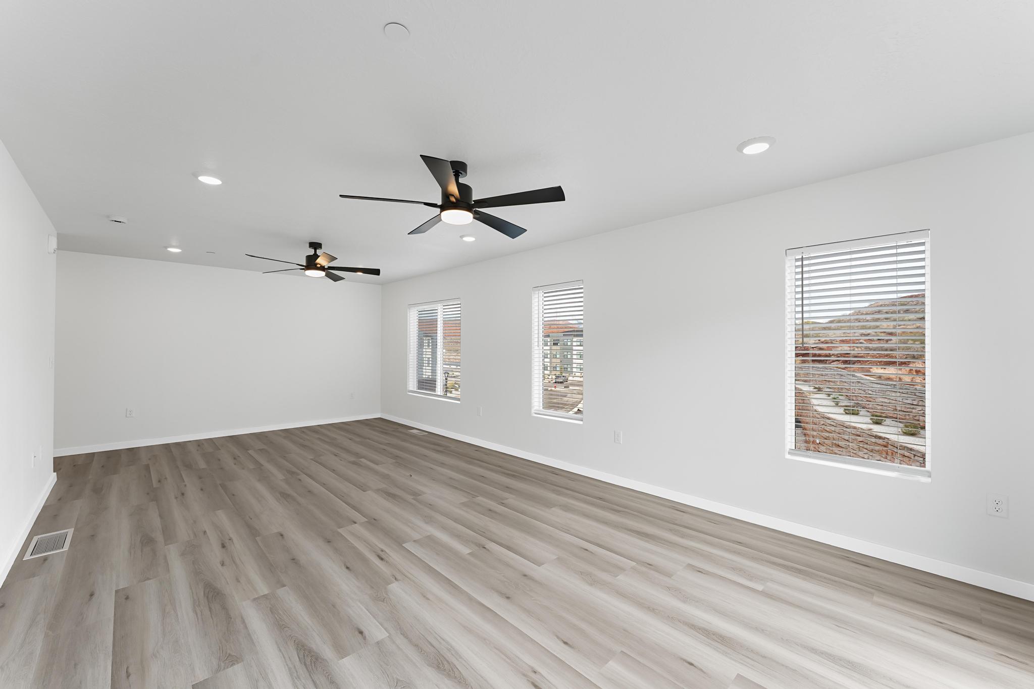 Spacious interior with neutral wall tones, wood-finish flooring, recessed lighting, and two ceiling fans