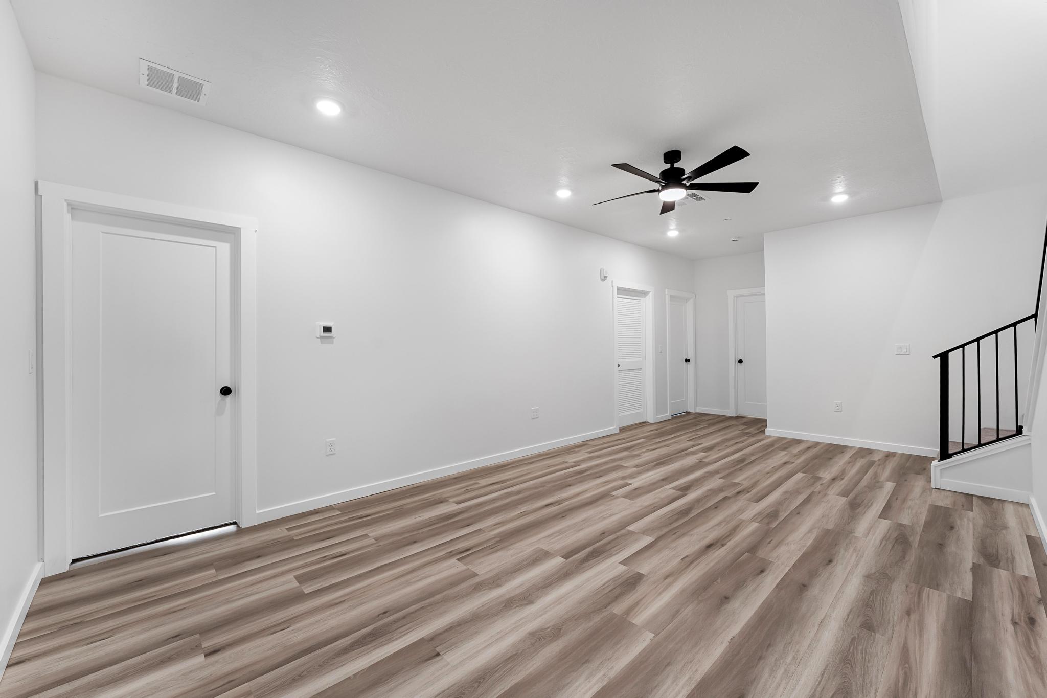 Spacious room with wood-finish flooring, white walls, and recessed lighting