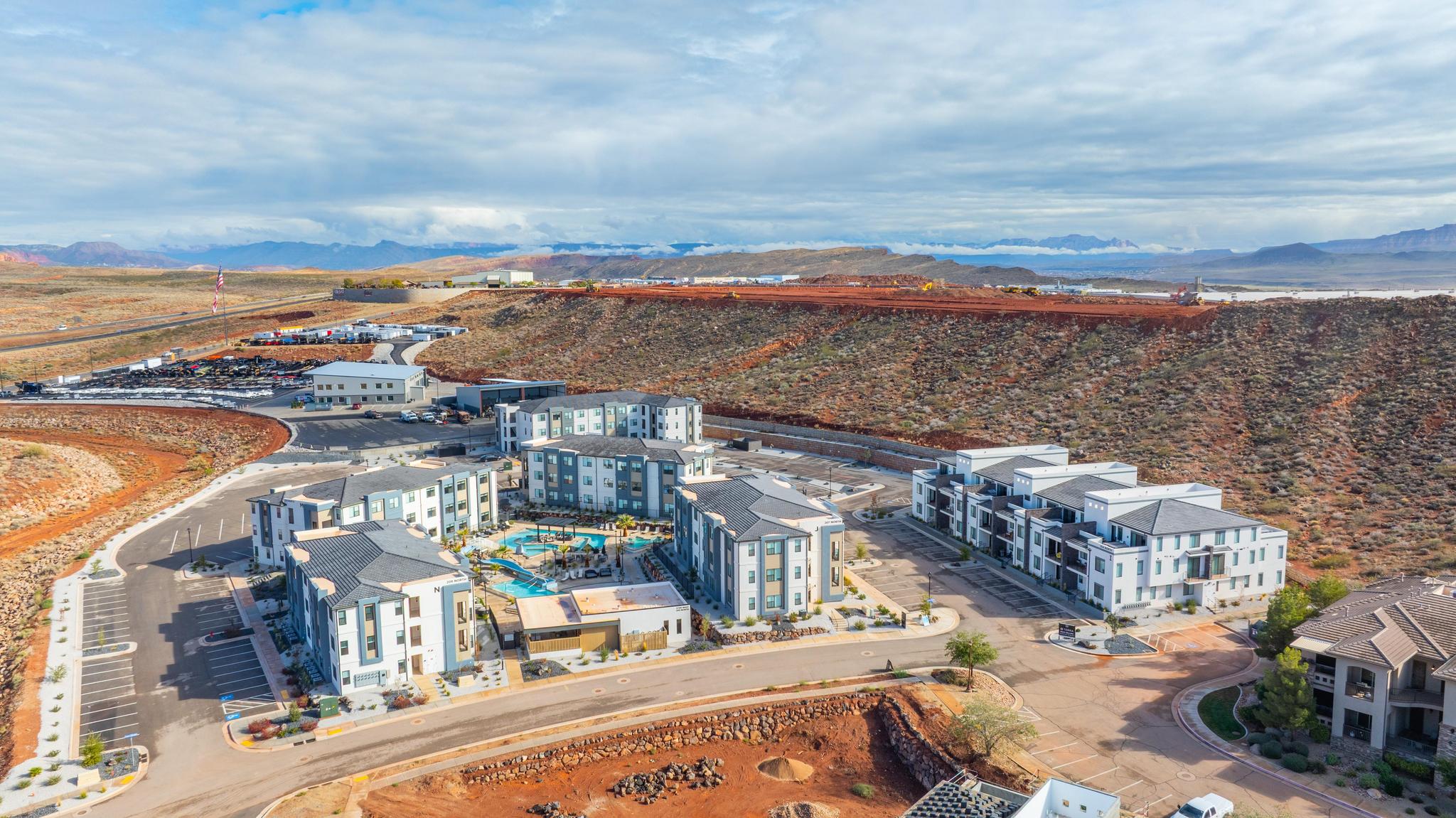 Contemporary multi-story buildings featuring varied exterior finishes, abundant surface parking, and a central aquatic area