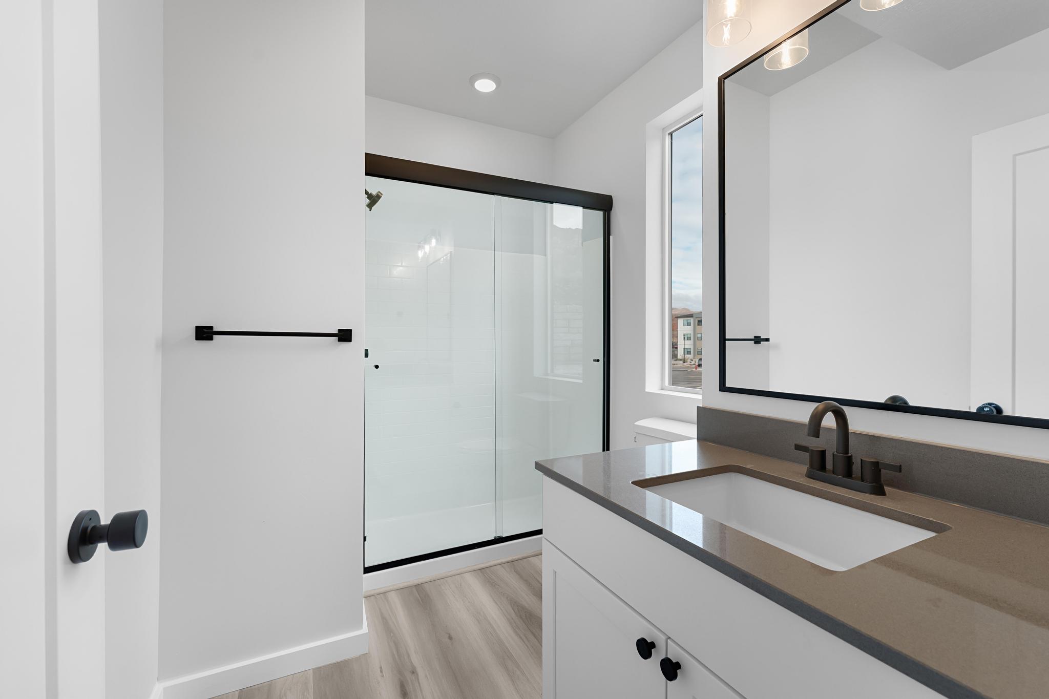 Modern bathroom featuring a single vanity with a neutral-toned countertop and an integrated white sink