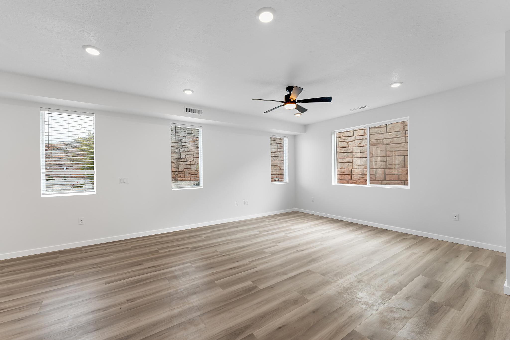 Spacious room featuring wood-finish flooring, recessed lighting, and a ceiling fan