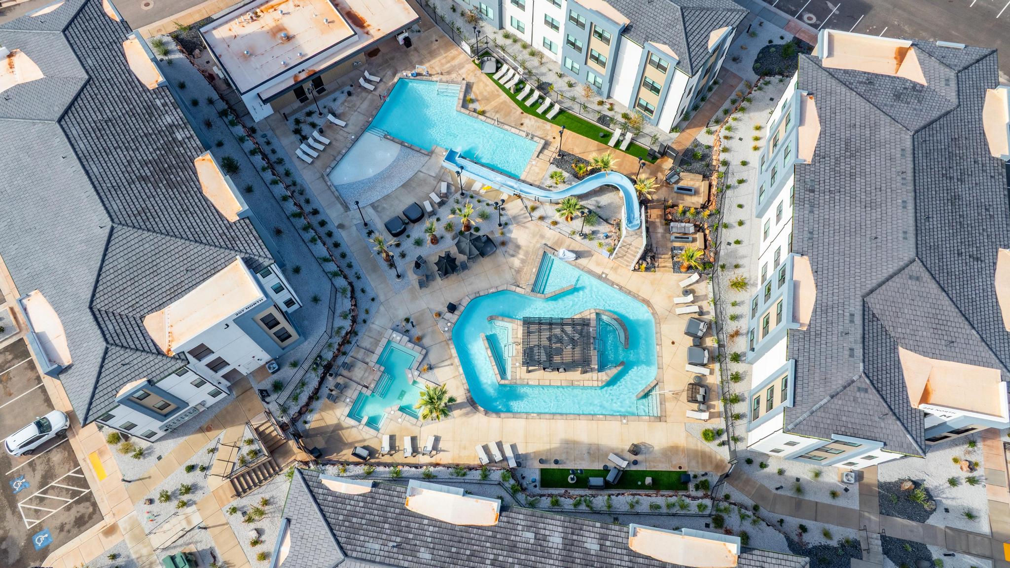 Expansive multi-pool complex featuring a lazy river, a swimming pool with an attached water slide, and ample lounge seating