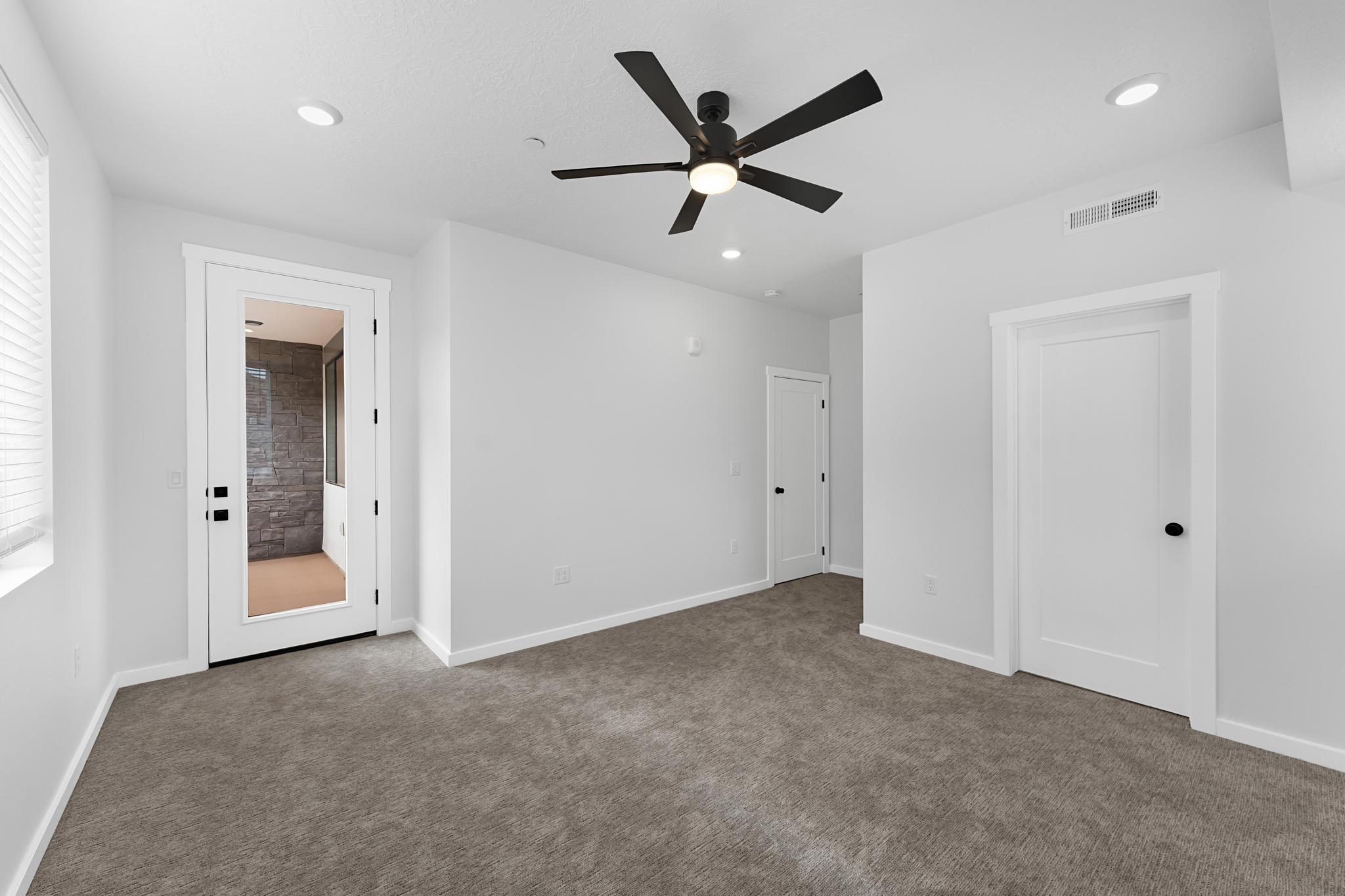 Spacious room featuring neutral carpeting, a modern ceiling fan, recessed lighting, and crisp white trim