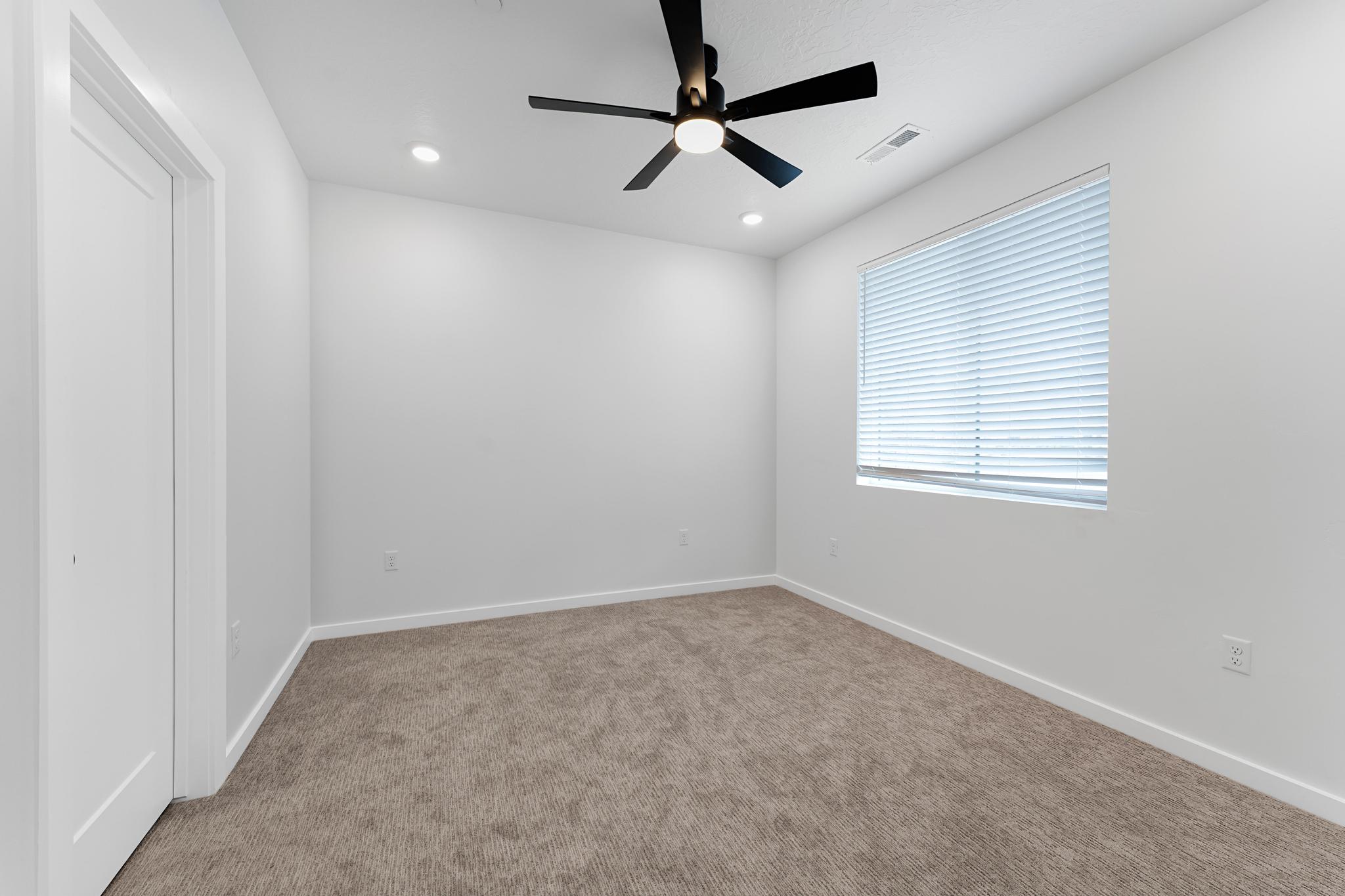 Bright interior space featuring a ceiling fan with integrated lighting, recessed ceiling lights, and a window with horizontal blinds