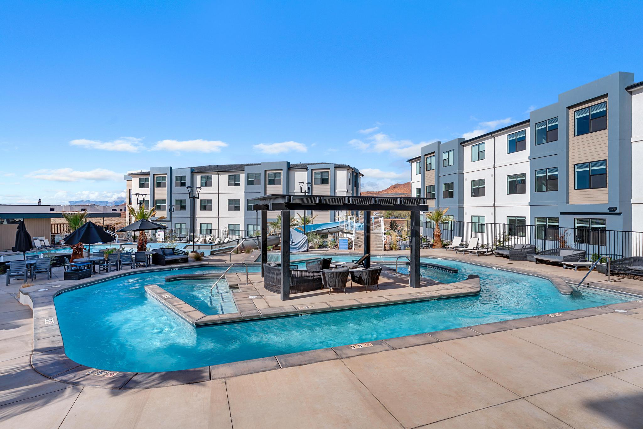 Resort-style pool area featuring a lazy river, an integrated spa, and an entertainment island with pergola