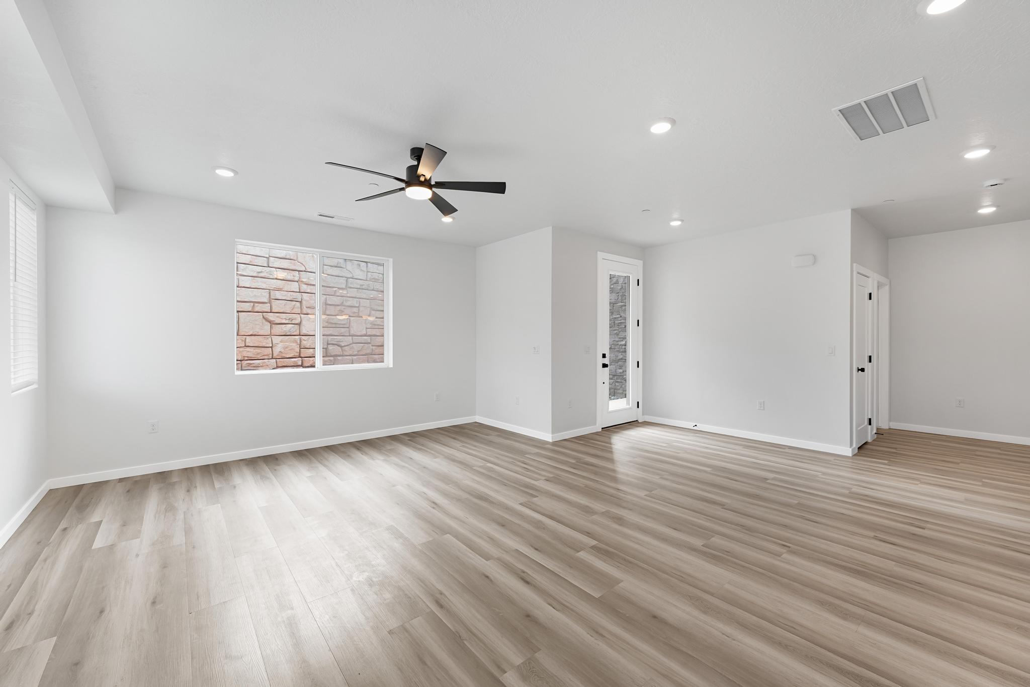 Spacious room featuring wood-finish flooring, recessed lighting, and a contemporary ceiling fan