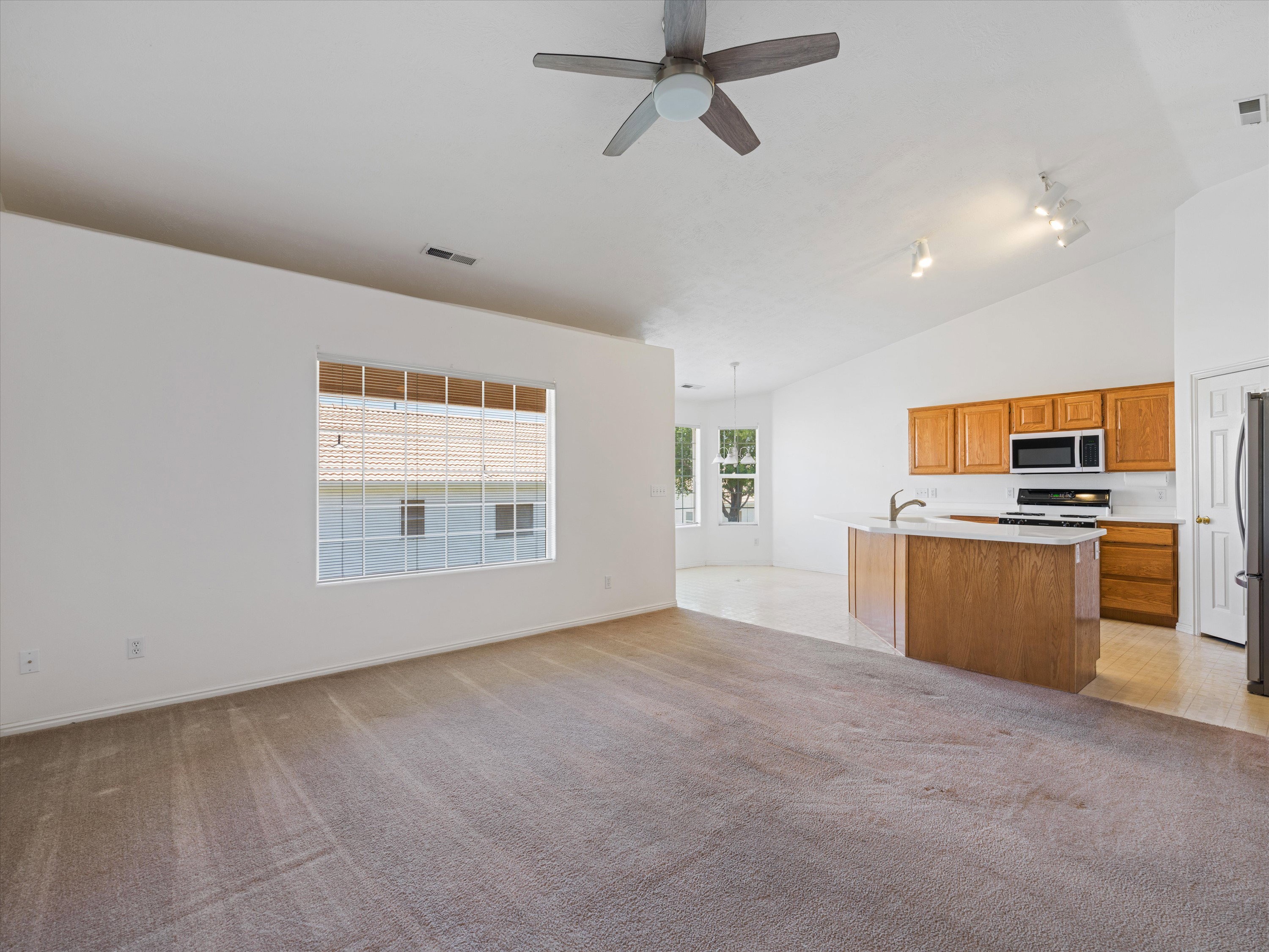 Open-concept living space featuring a vaulted ceiling and a ceiling fan