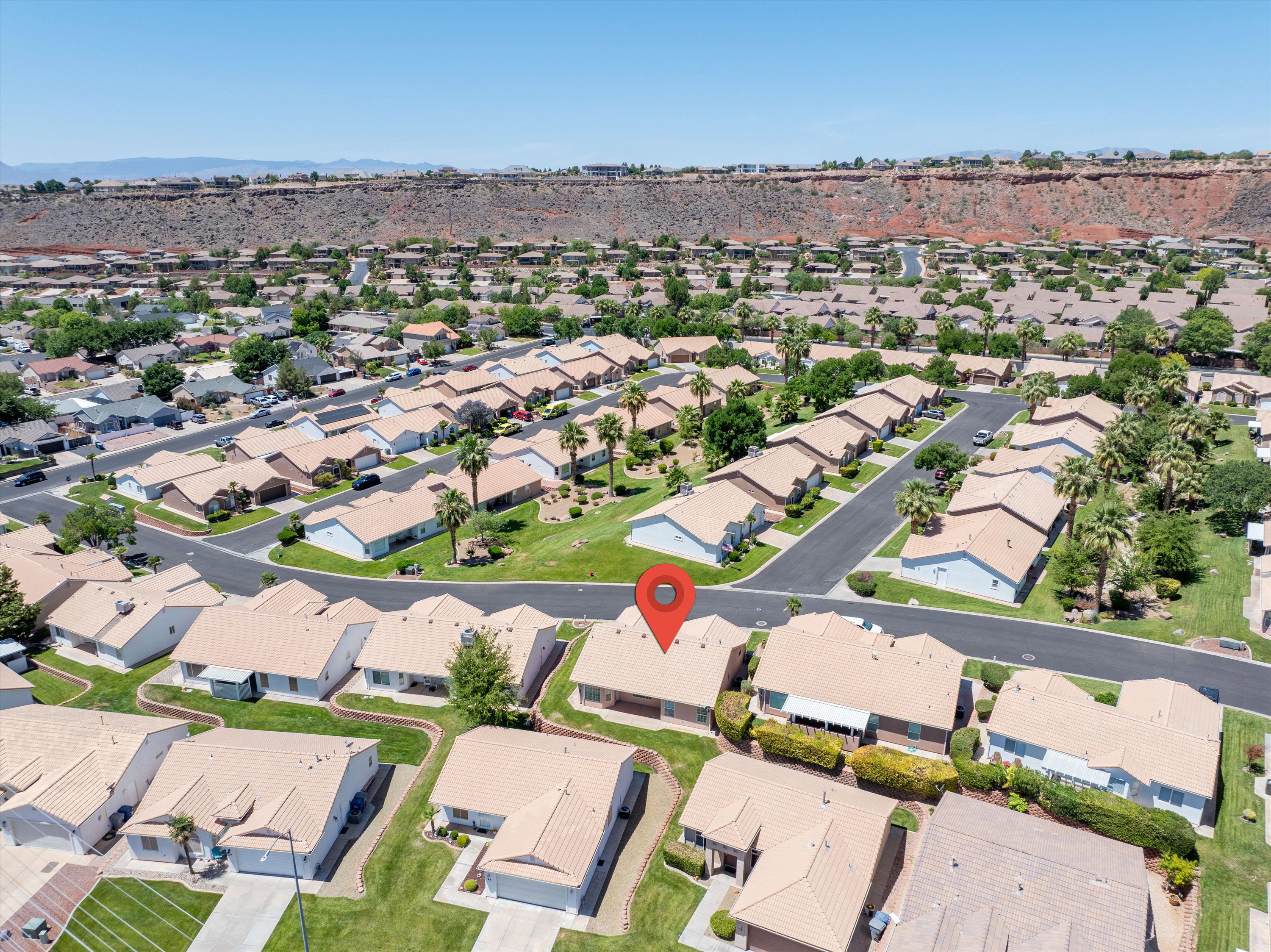 Aerial perspective showcasing a residential community with uniform tan roofs, surrounded by lush green landscaping and mature palm trees