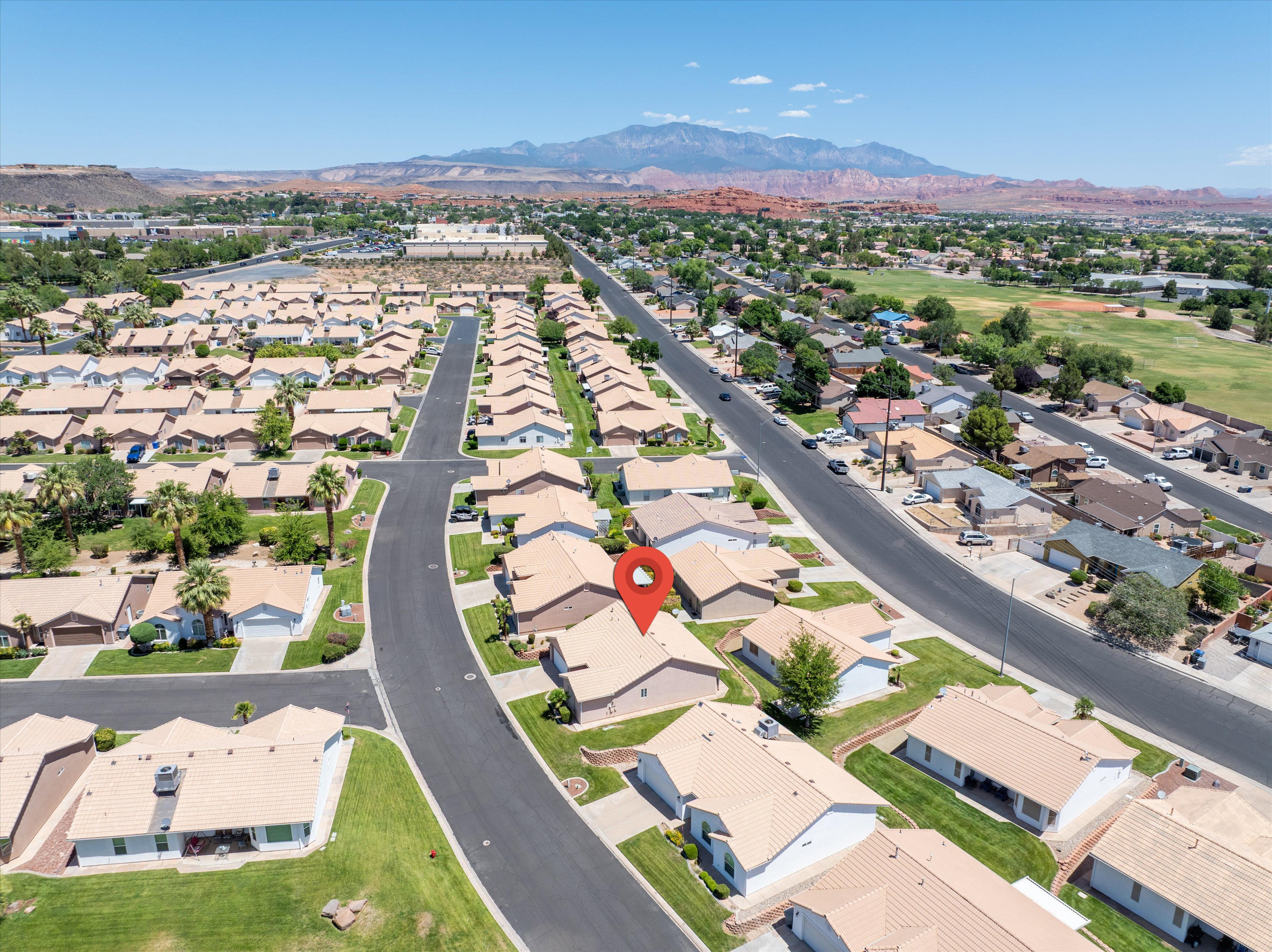 Aerial perspective of a residential community featuring single-story homes with light-colored roofs