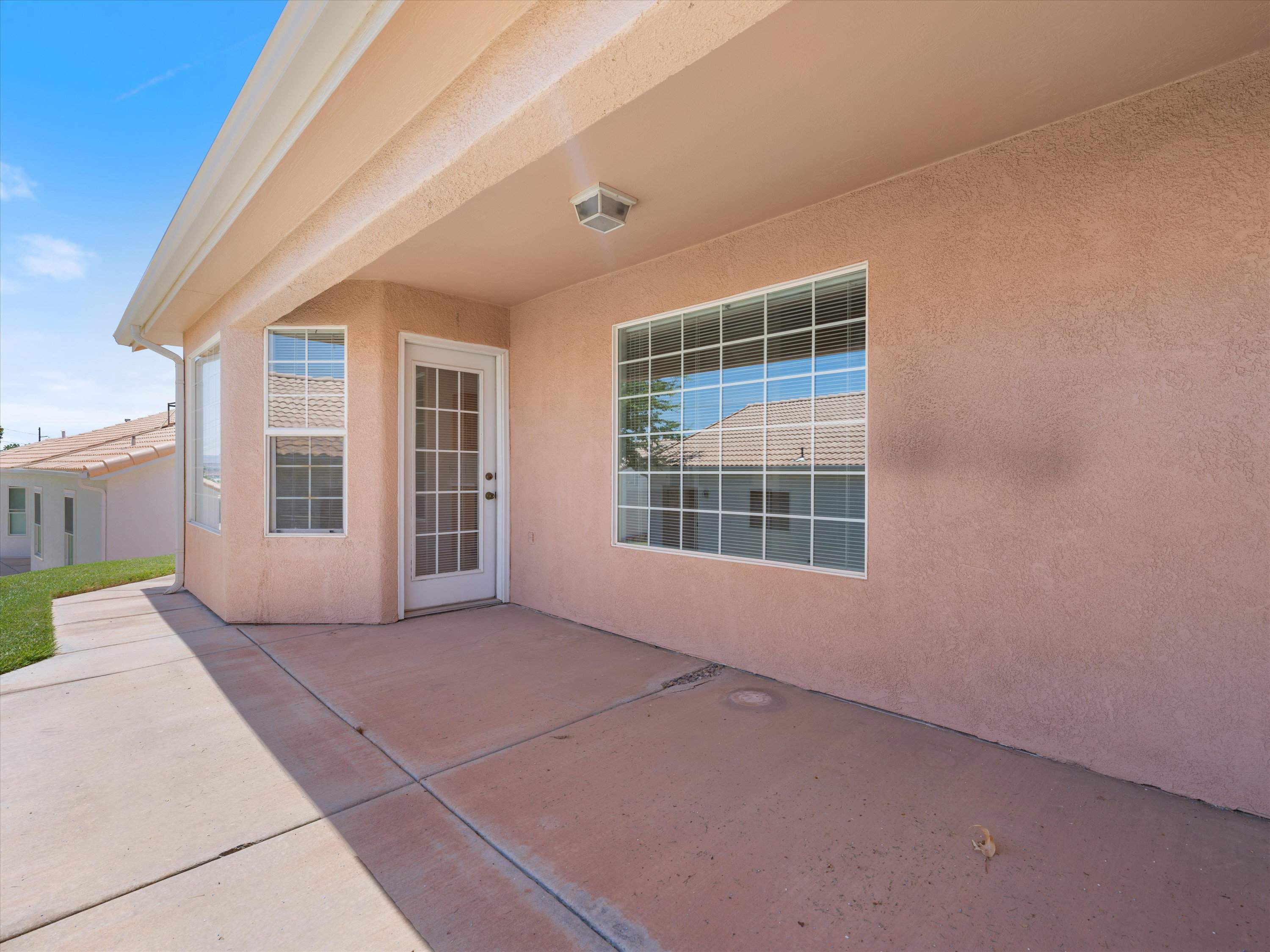 Covered patio featuring a stucco exterior, concrete flooring, and multiple window-paned doors