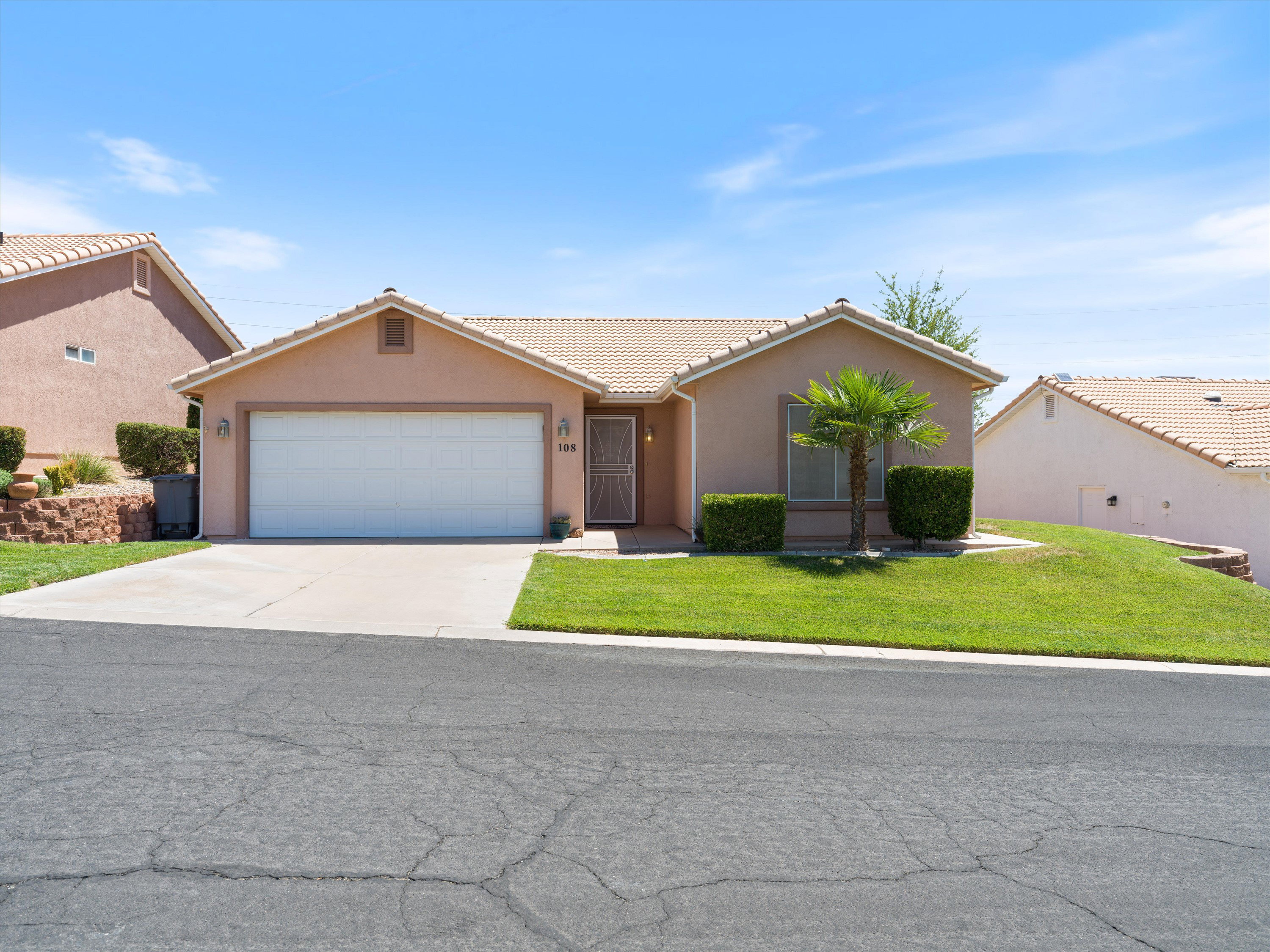 Stucco exterior home featuring a two-car garage, concrete driveway, and front lawn