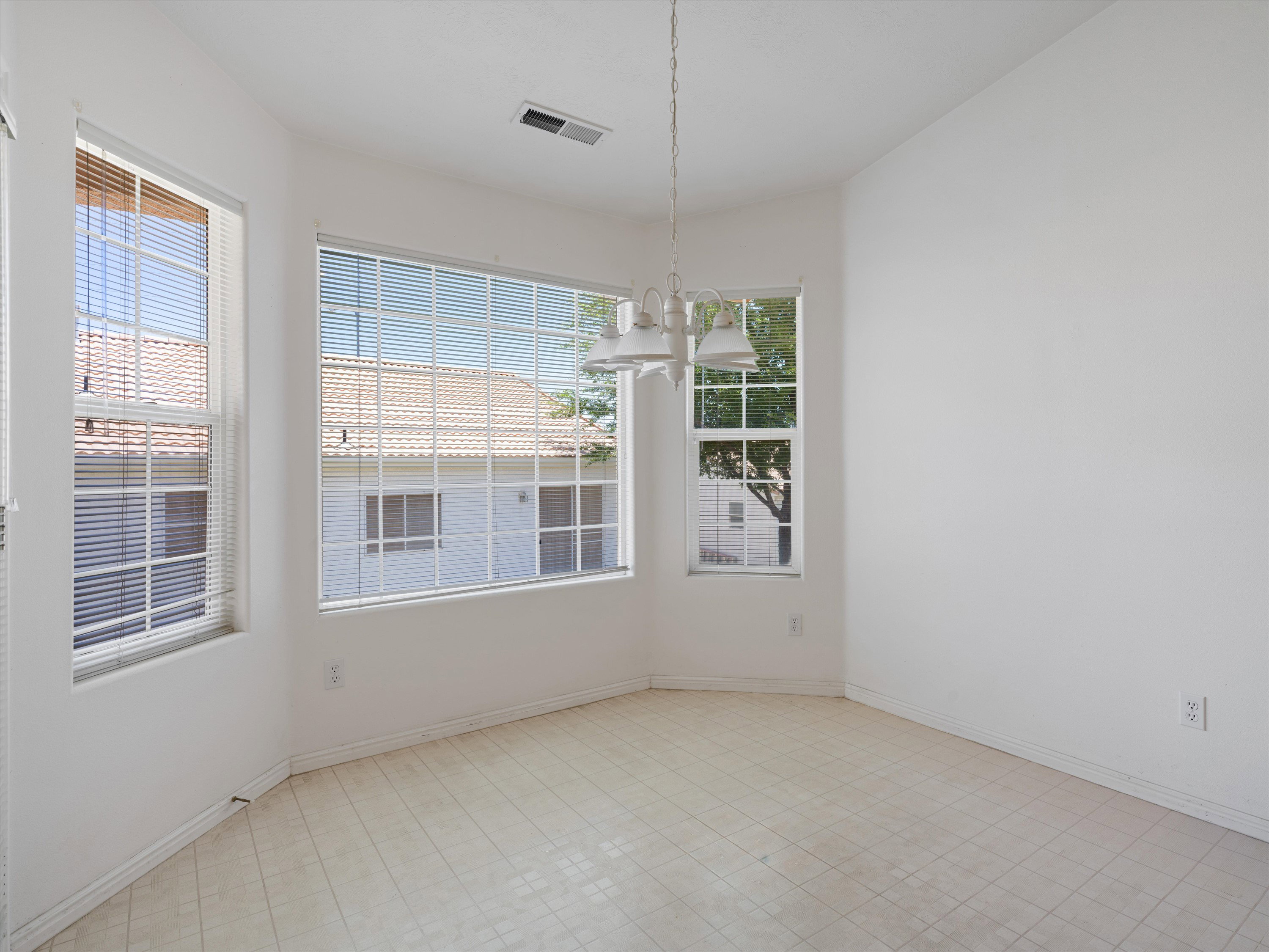 Dining area featuring bay windows, white window blinds, a white chandelier, and light-toned flooring