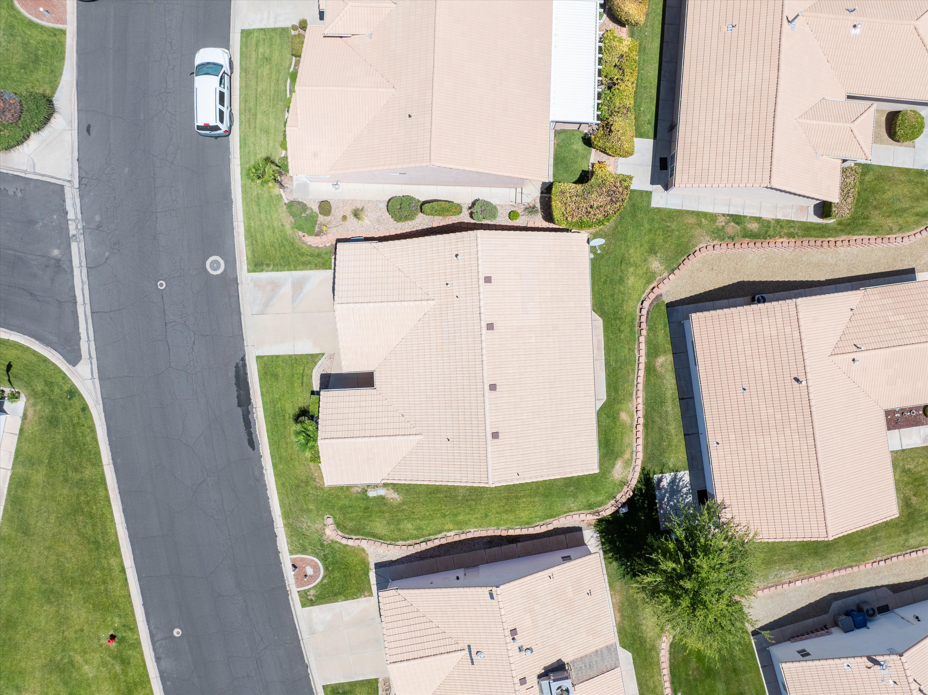 Overhead residential property featuring a tan tile roof, green lawn, and concrete driveway