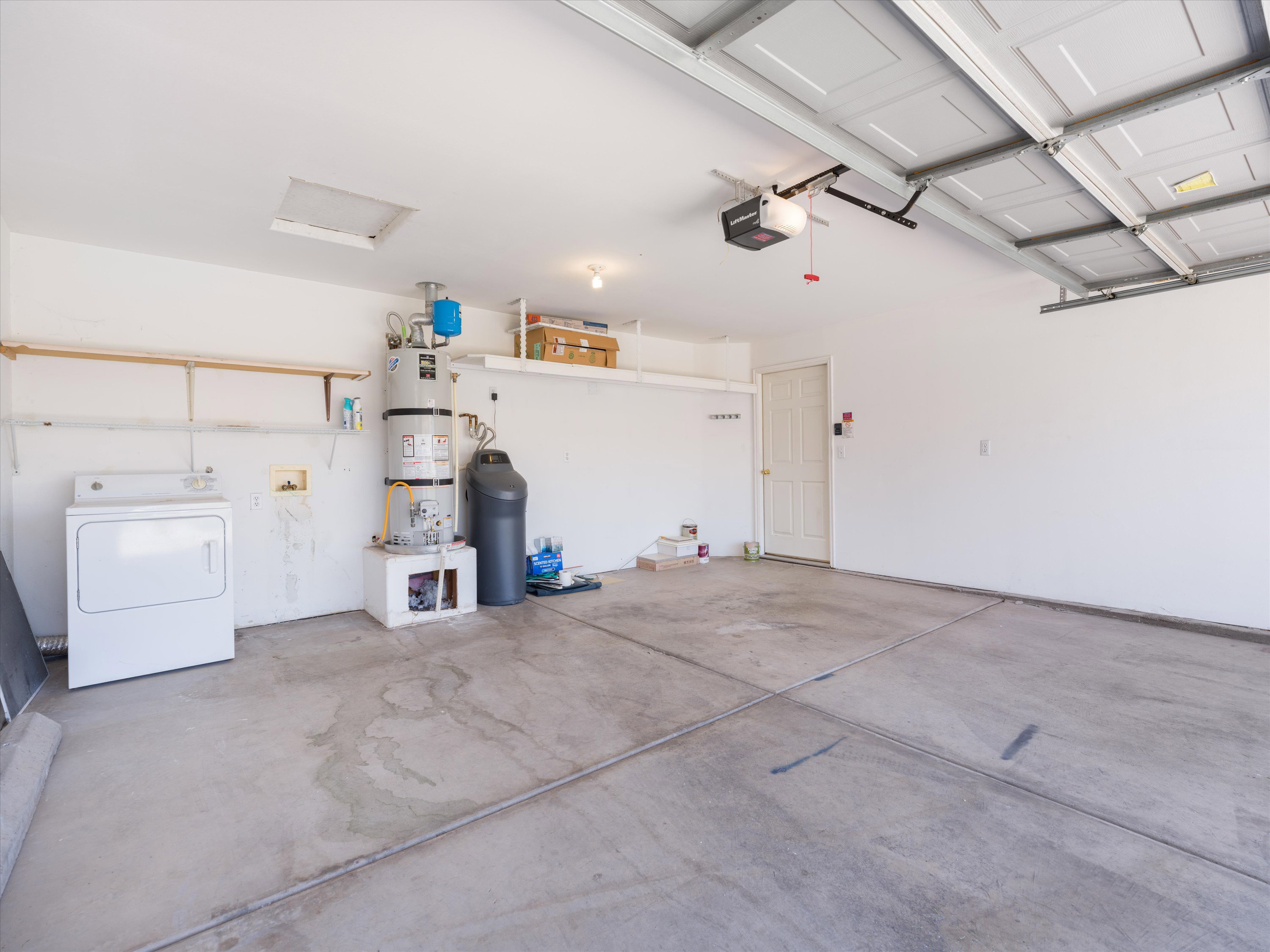 Spacious garage featuring a concrete floor, overhead garage door with opener, and white painted walls