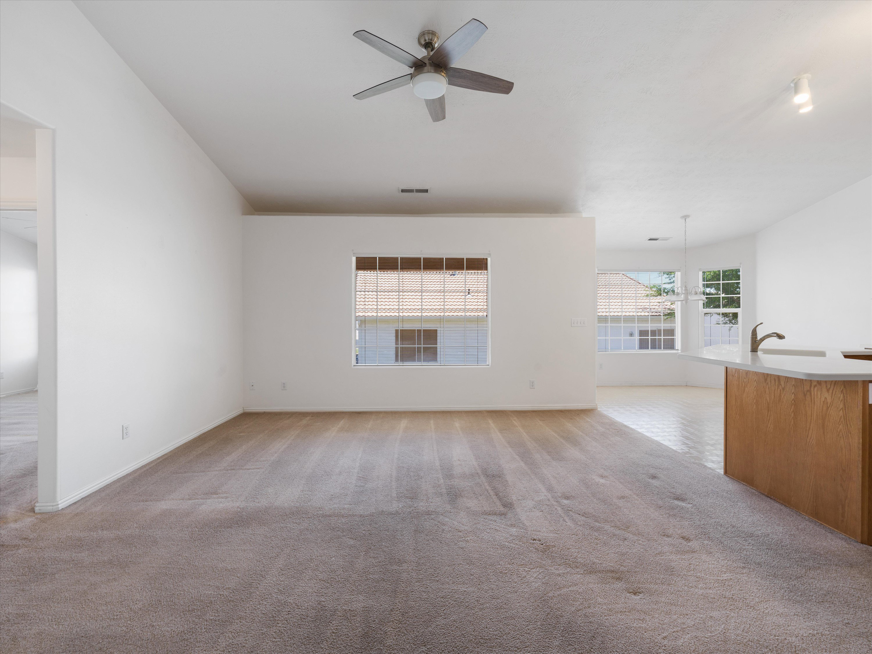 Spacious interior with neutral carpeting and a ceiling fan