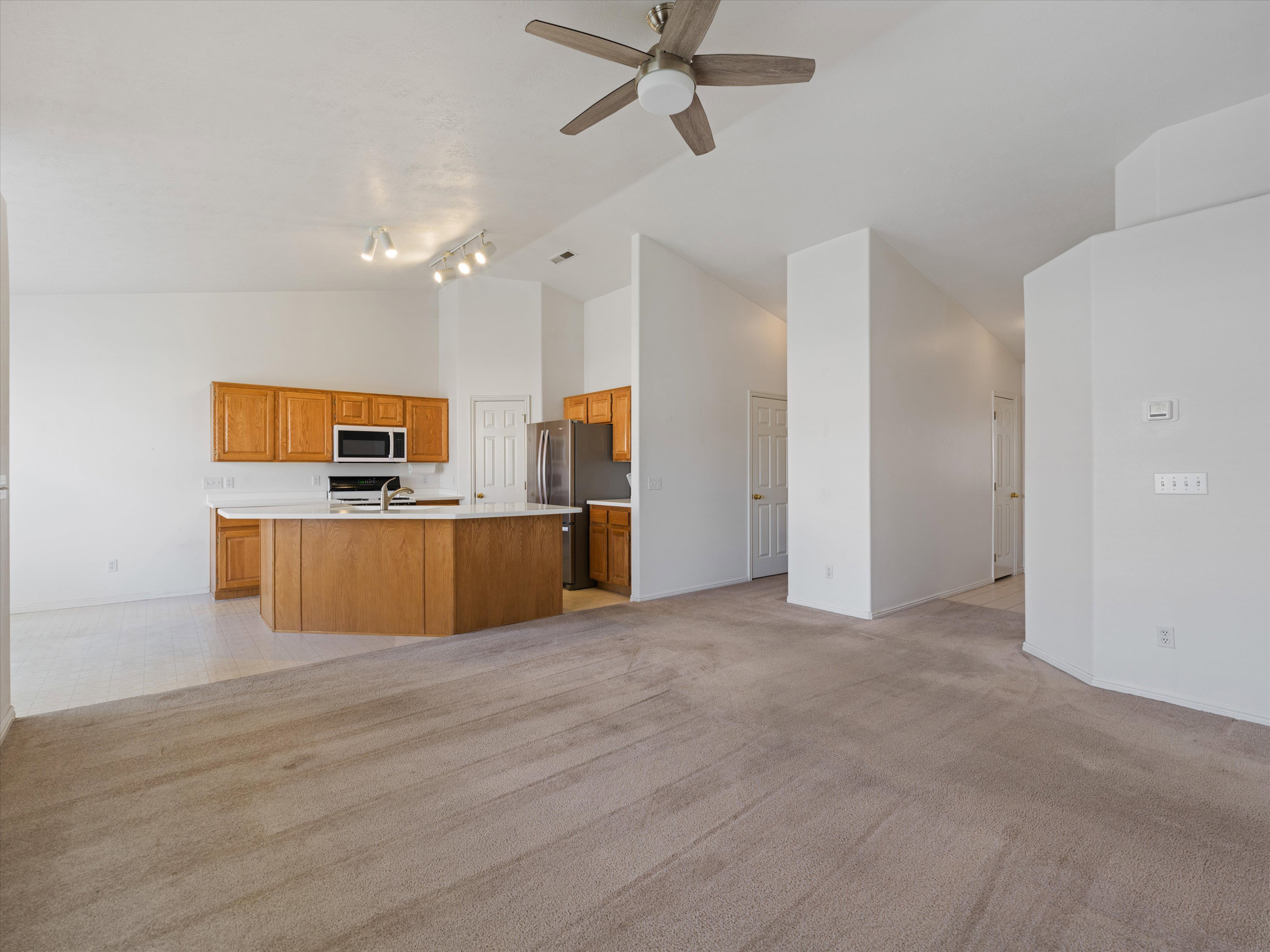 Open concept living area featuring vaulted ceilings, a ceiling fan, and track lighting