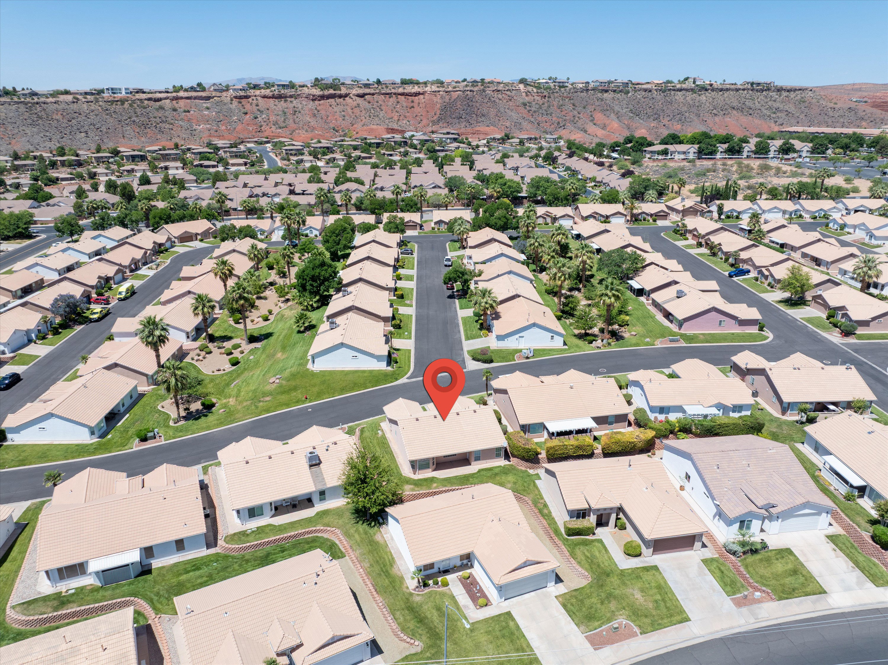 Aerial view of a residential community featuring single-story properties with tan roofs and light-colored exteriors