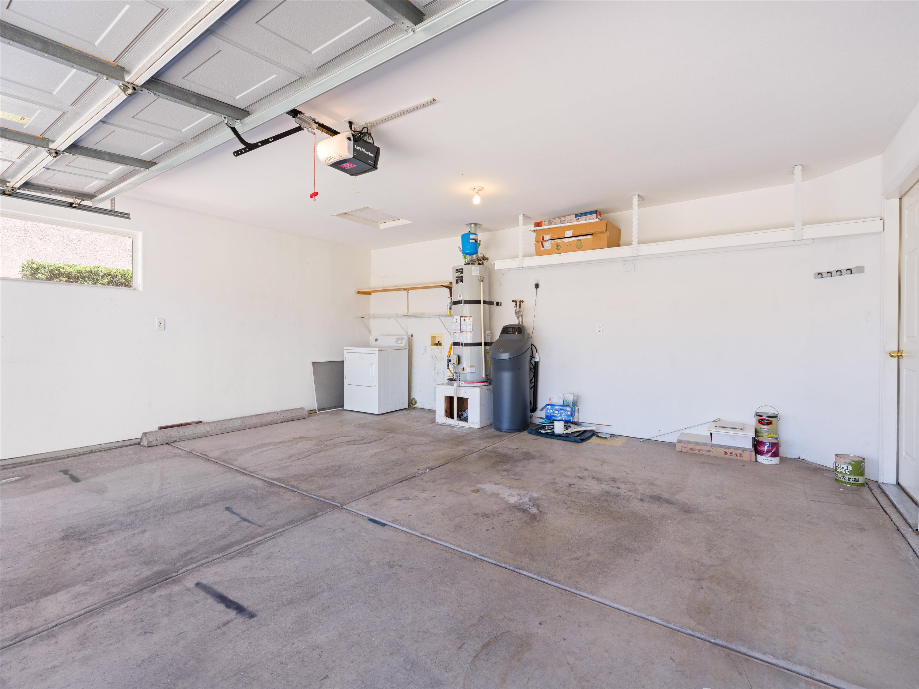 Spacious garage featuring a concrete floor, overhead garage door with opener, and a single window