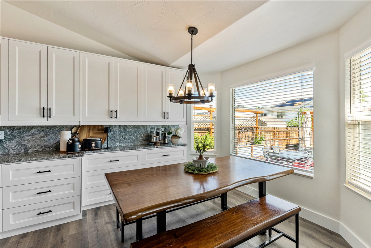 White shaker cabinetry with dark hardware, granite countertops, and full-height backsplash