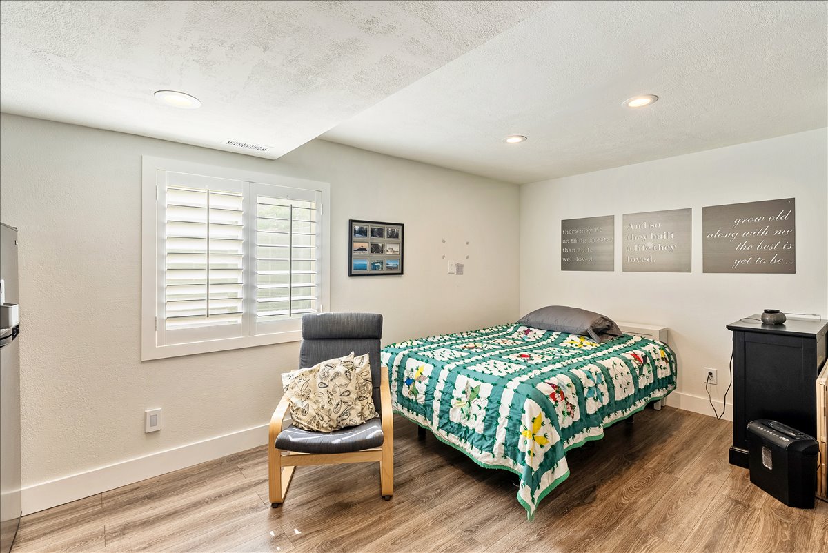 Room featuring wood-finish flooring, recessed lighting, and a window with white plantation shutters
