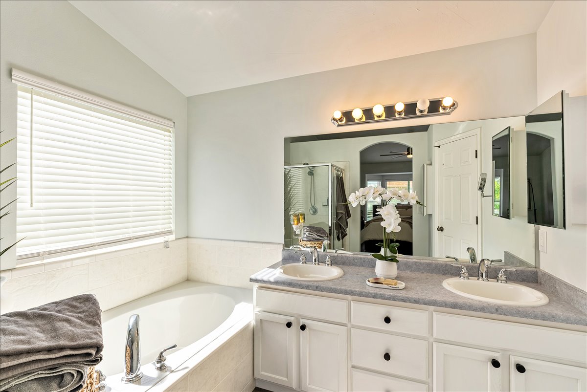 Bathroom featuring a dual vanity with a light-toned countertop and white cabinetry
