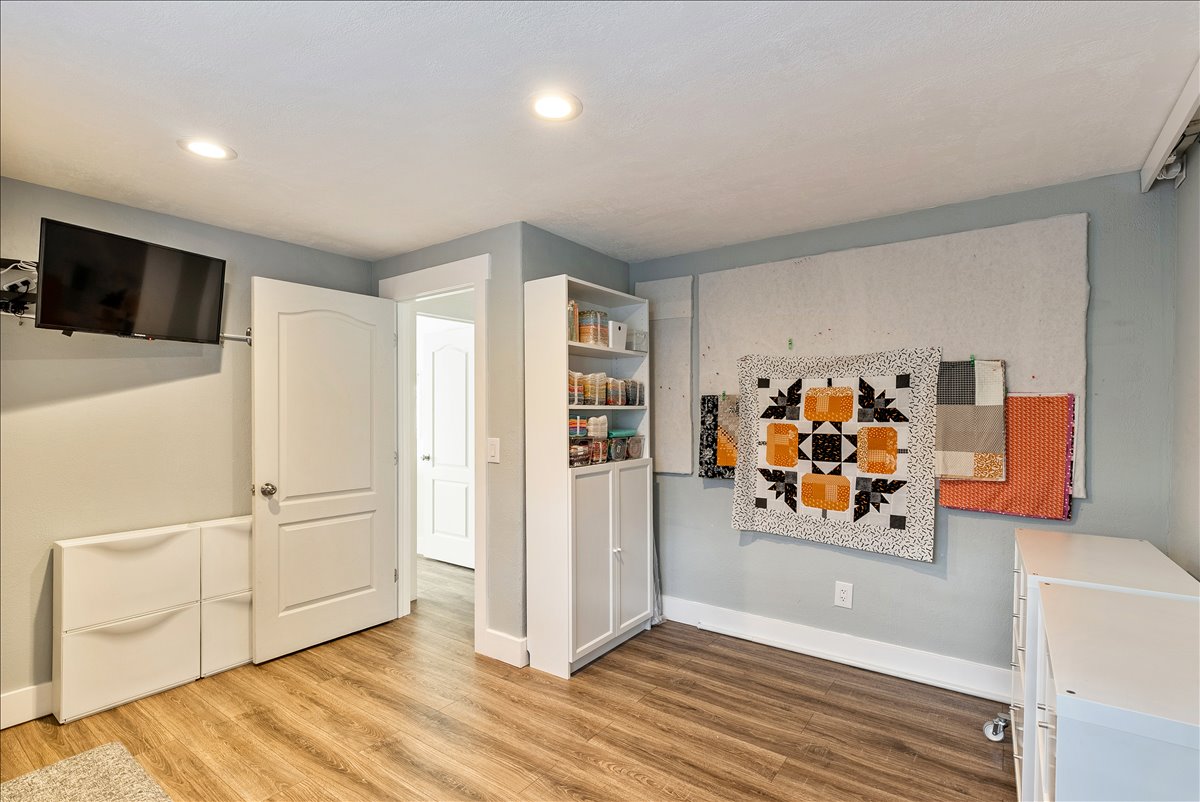 Room with wood-finish flooring, recessed lighting, and a white built-in storage cabinet