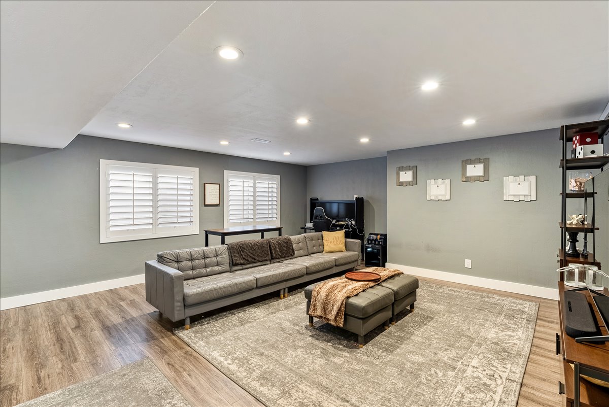 Spacious room featuring wood-finish flooring, recessed lighting, and two windows with white plantation shutters
